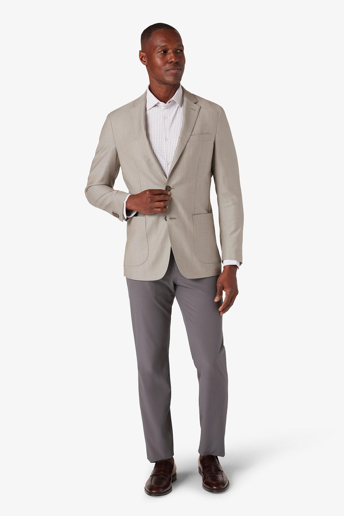 Man wearing a beige blazer and gray pants on a white background