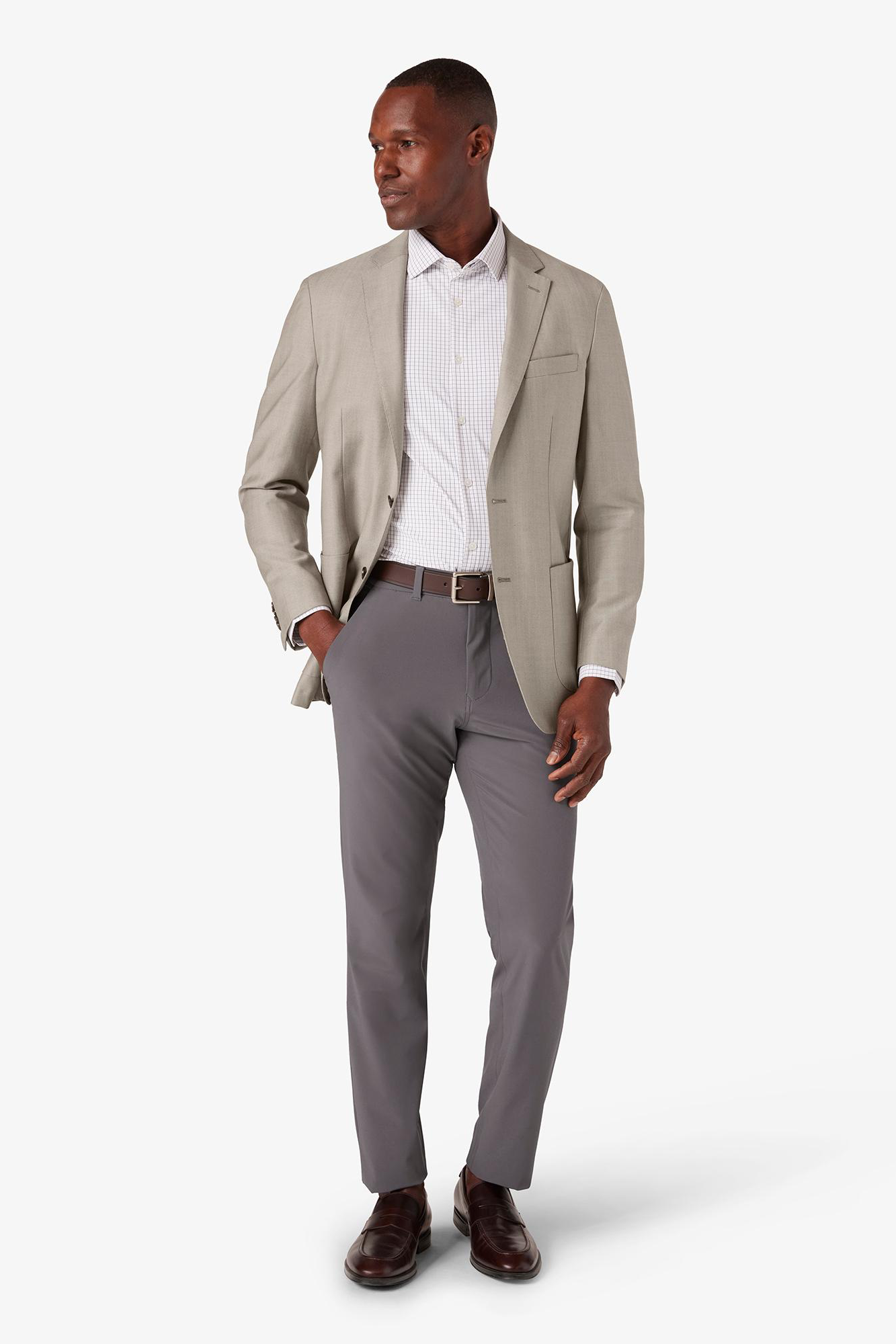 Man wearing a beige blazer and gray pants on a white background