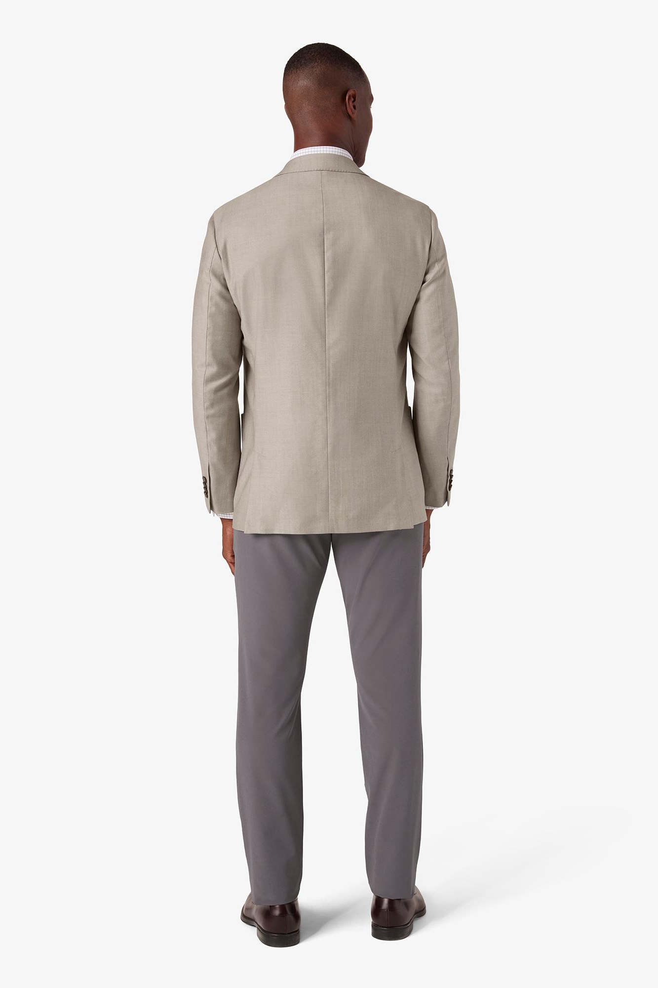 Man wearing a beige suit jacket and gray pants on a white background