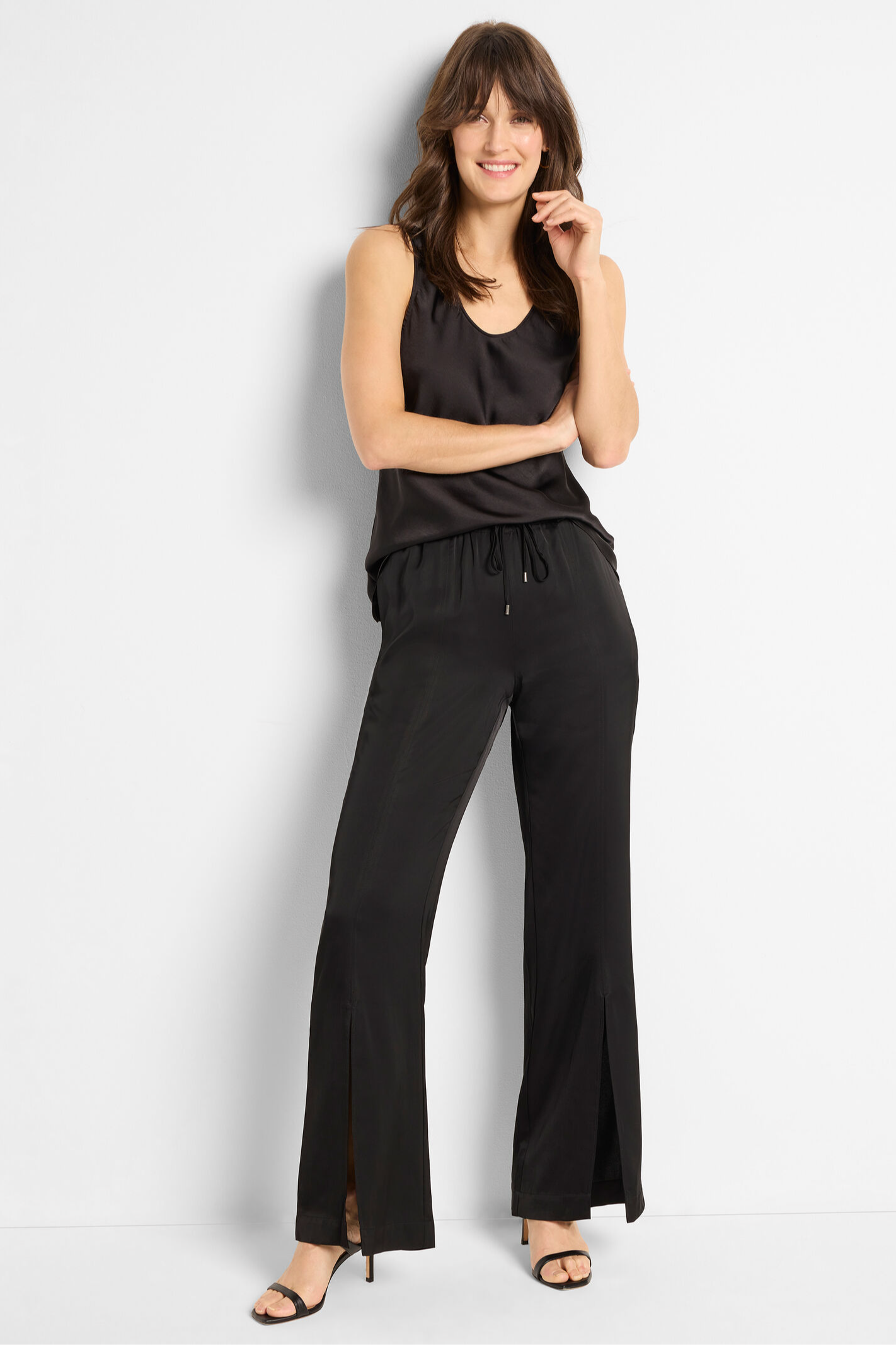 Woman wearing a black sleeveless top and pants against a white background