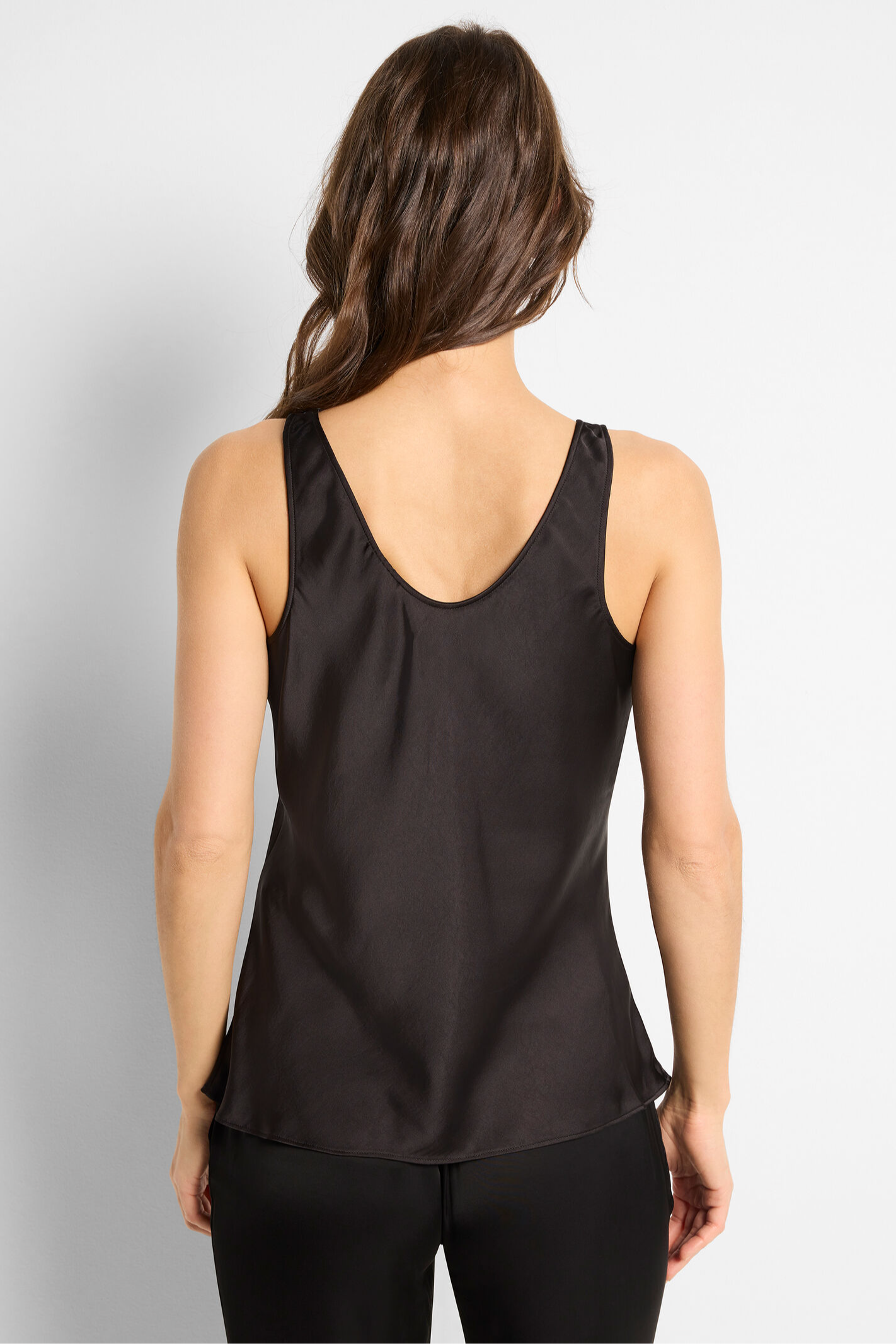 Woman wearing a black sleeveless top against a plain background