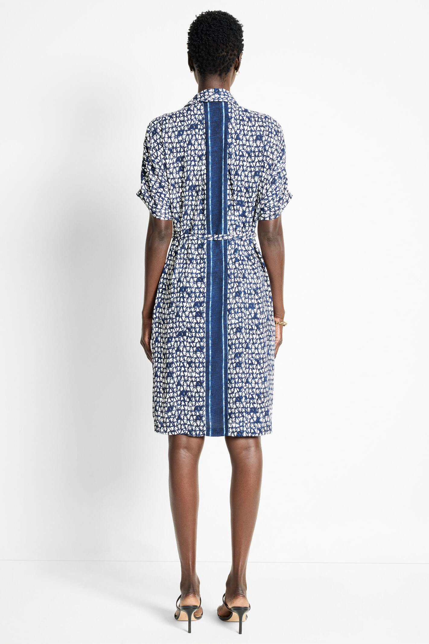 Woman wearing a patterned dress with a belt on a white background