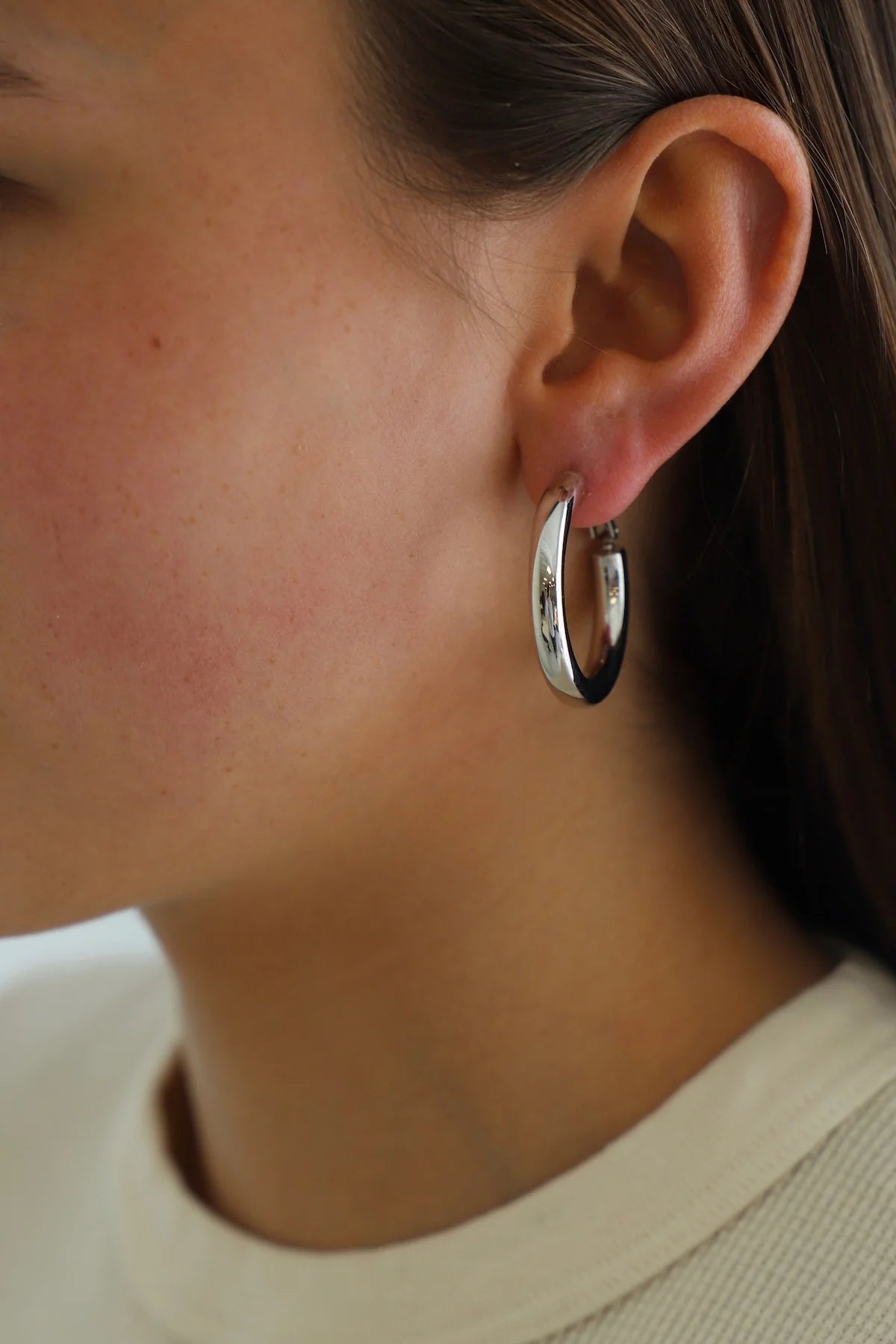 Close-up of a person wearing a silver hoop earring.