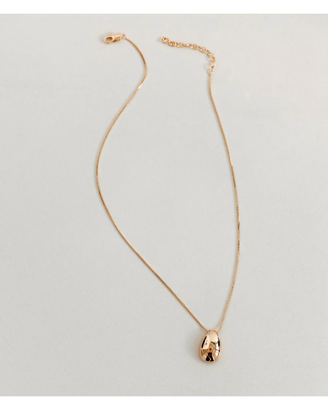 Gold necklace with a pendant on a light gray background