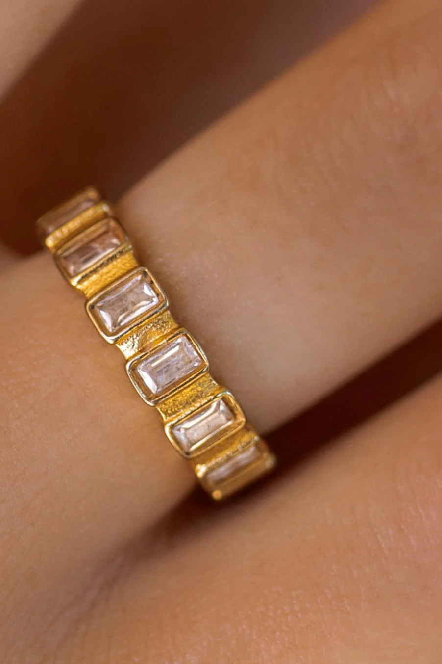 Gold ring with a textured band worn on a finger