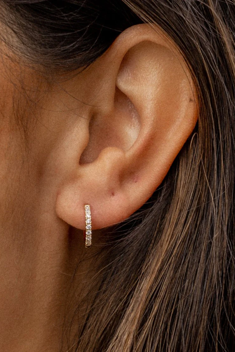 Close-up of an ear wearing a diamond hoop earring.