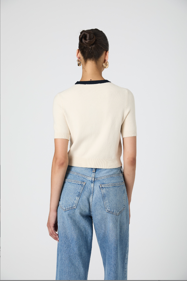 Person wearing a cream sweater and blue jeans from behind on a white background