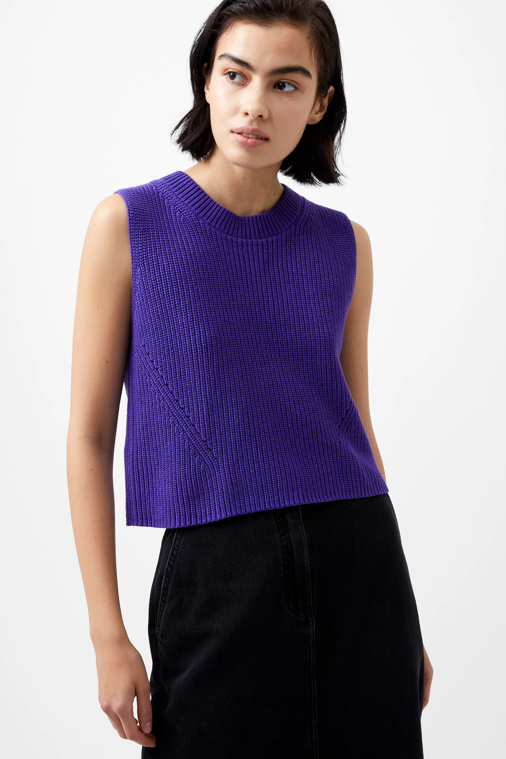 Woman wearing a purple sleeveless knitted top against a white background