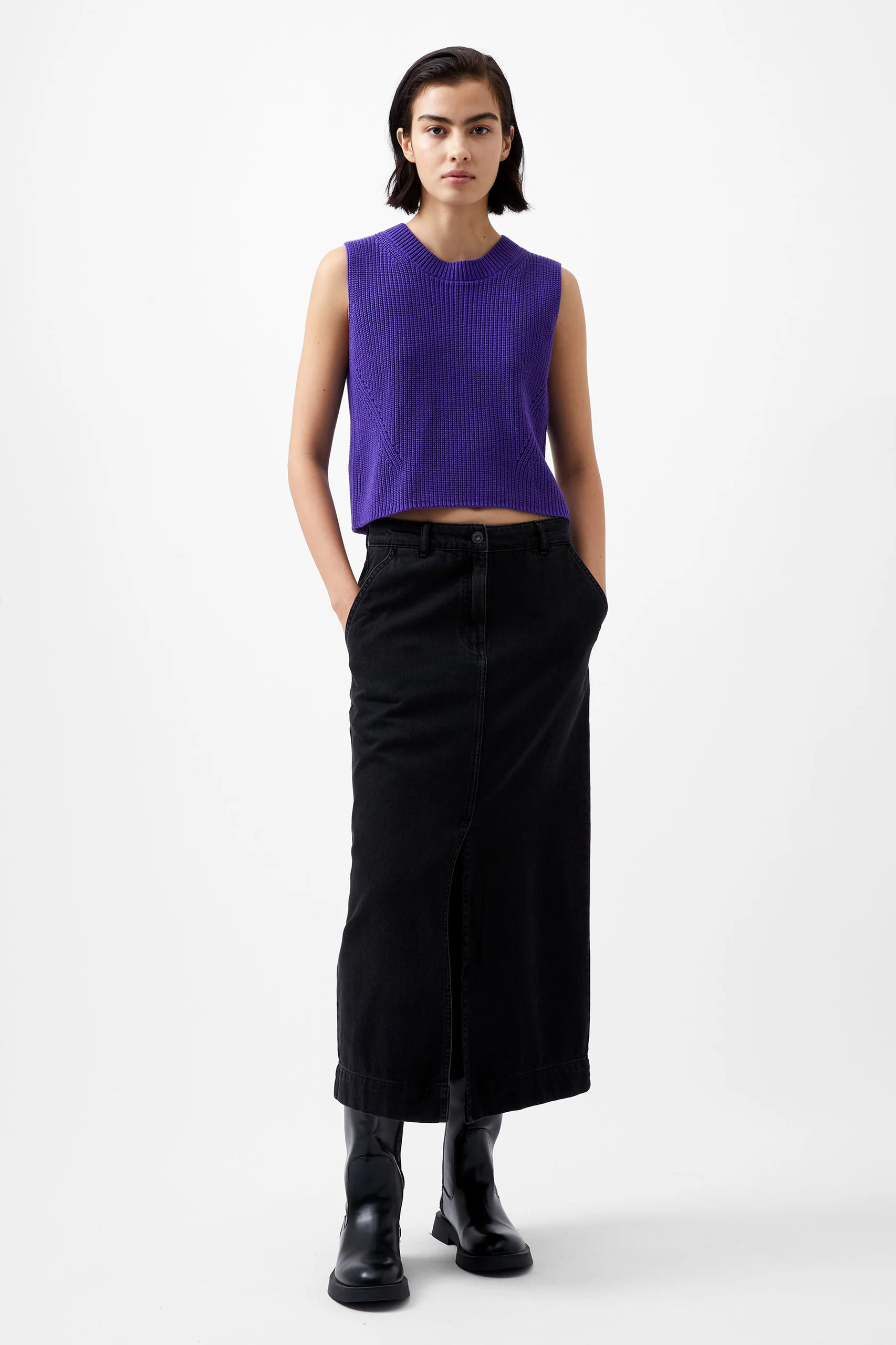 Person wearing a purple sleeveless top and black skirt on a white background
