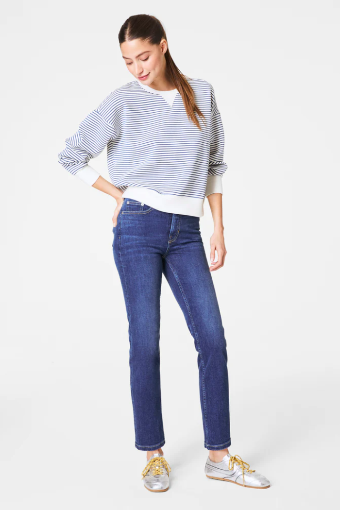 Woman wearing a striped sweater and blue jeans on a white background