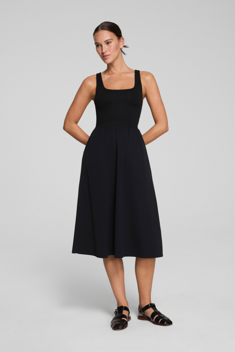 Woman wearing a black sleeveless dress on a light gray background