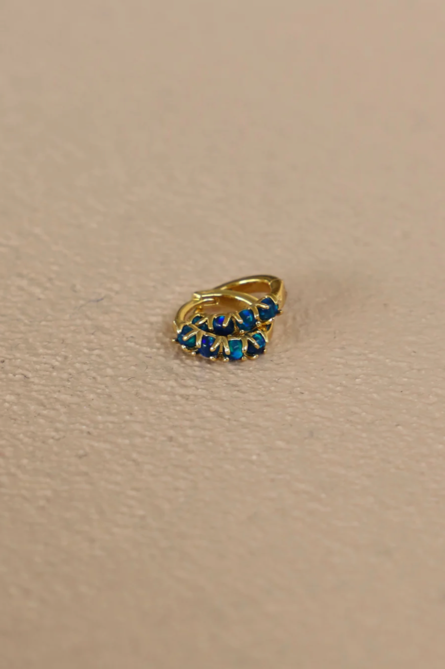 Gold ring with blue gemstones on a beige background