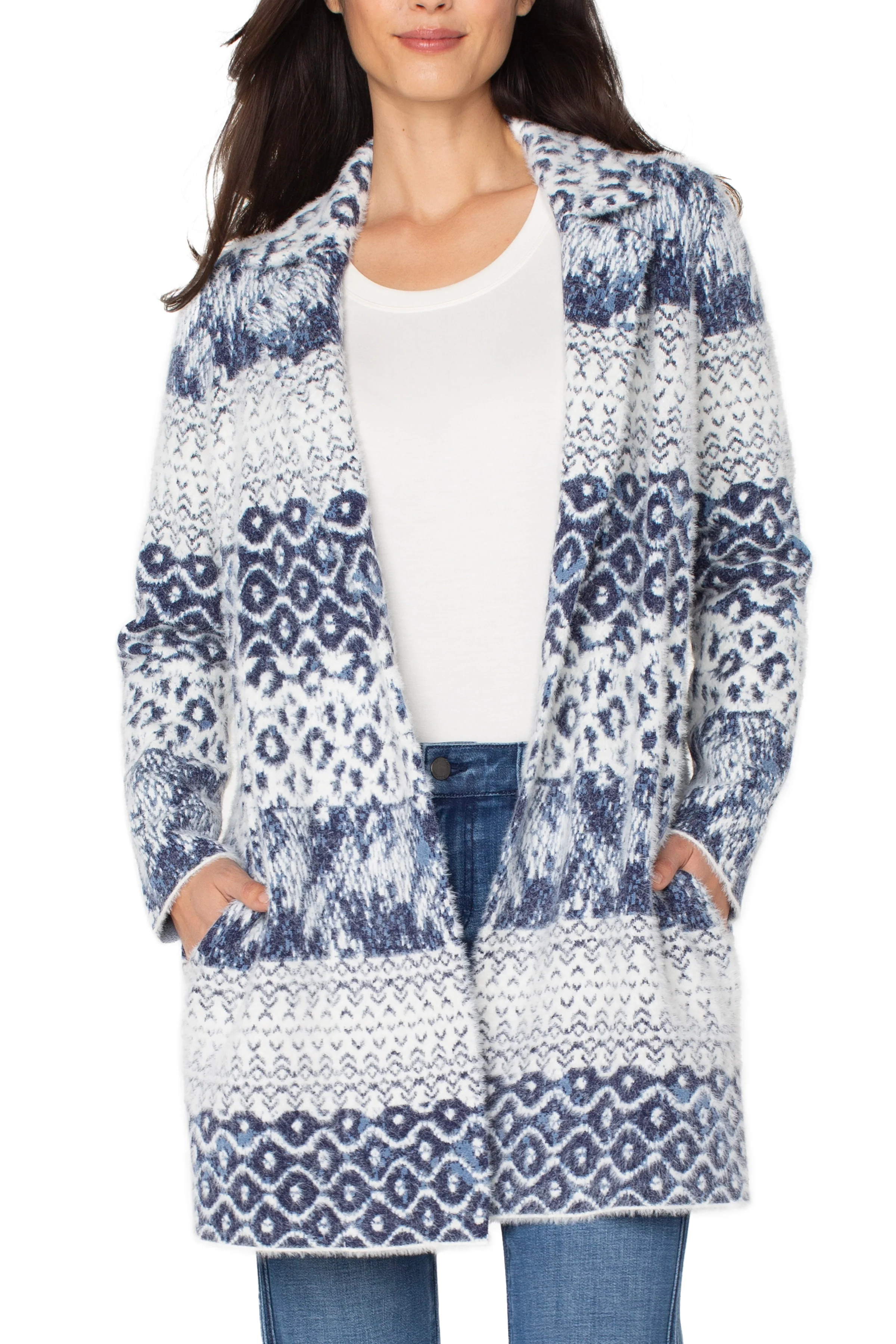 Woman wearing a blue and white patterned cardigan over a white shirt and jeans.