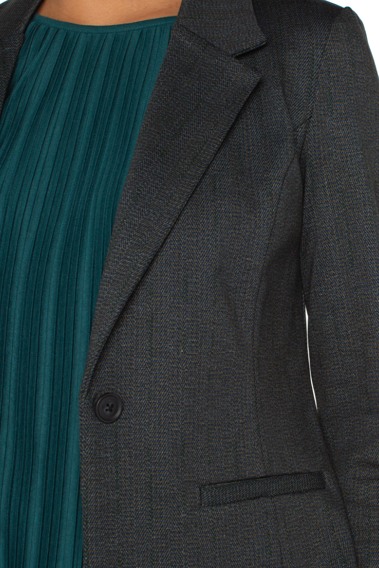 Dark gray blazer worn over a teal dress