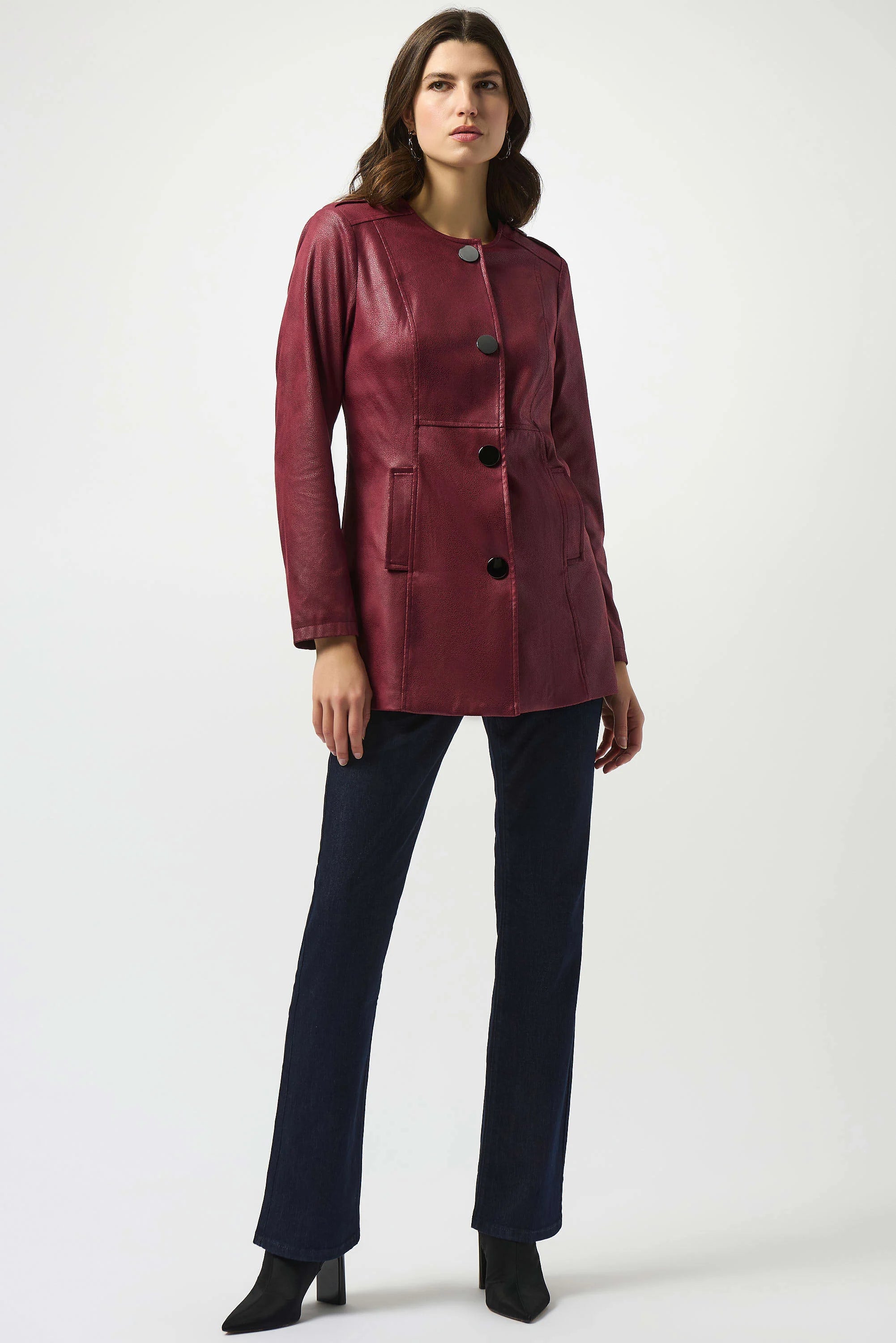 Woman wearing a burgundy jacket and dark pants on a white background