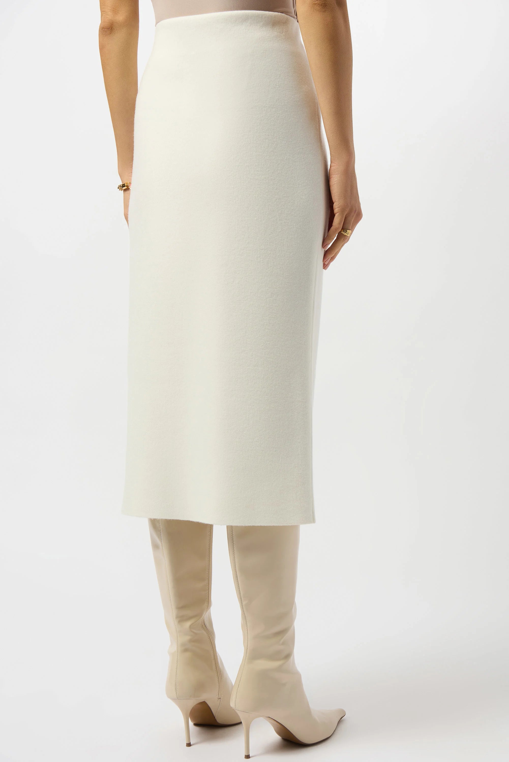 Person wearing a white skirt and beige high-heeled boots on a white background