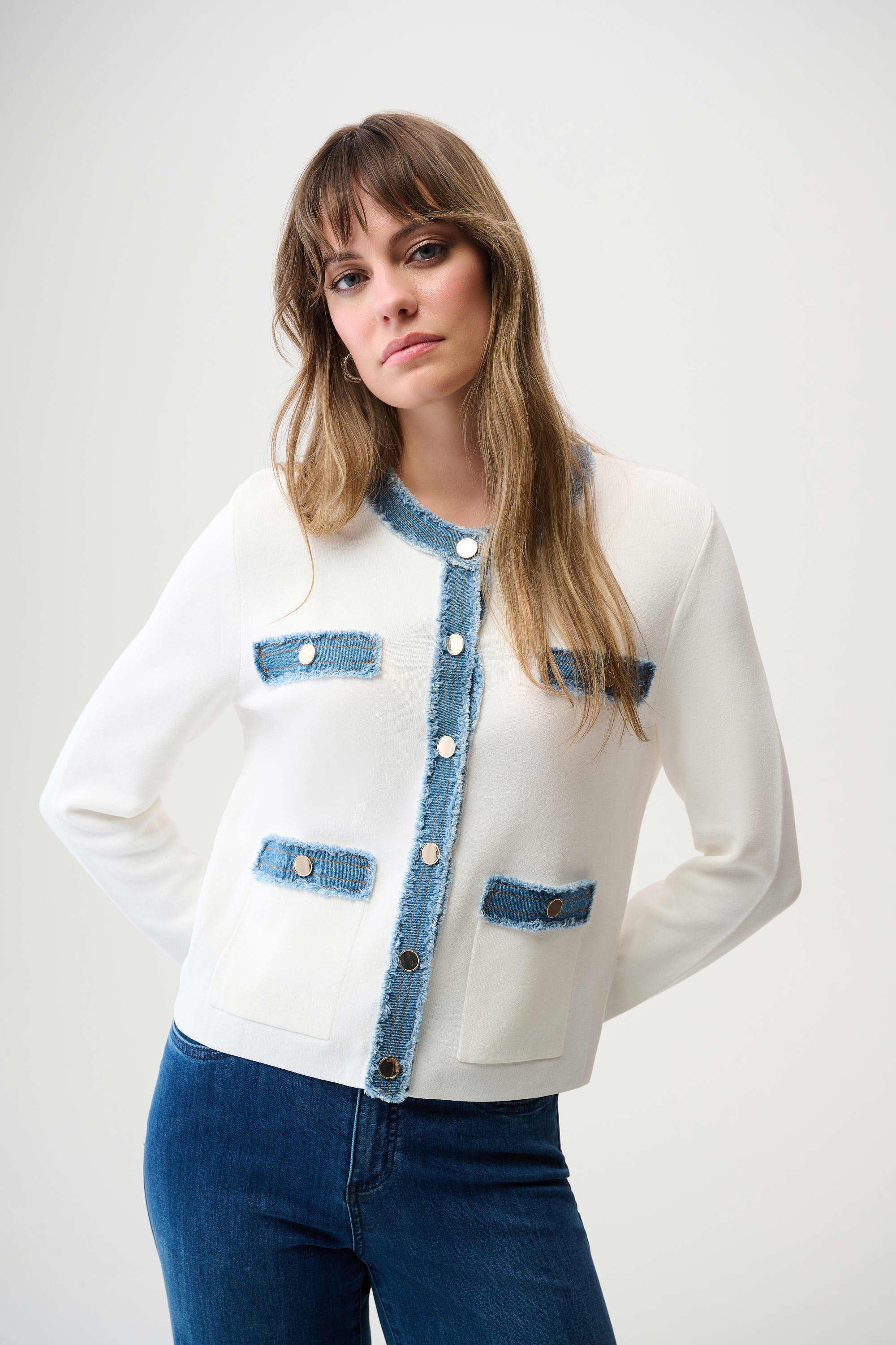 Woman wearing a white cardigan with blue accents on a plain background