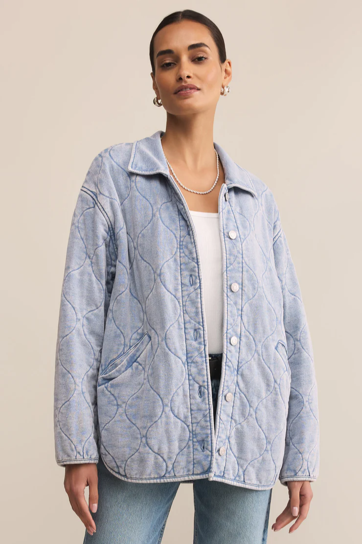 Woman wearing a light blue quilted jacket on a beige background