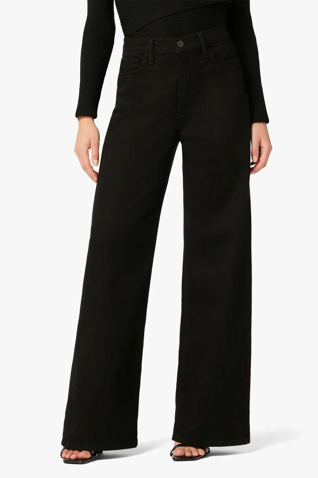 Person wearing black wide-leg jeans on a white background