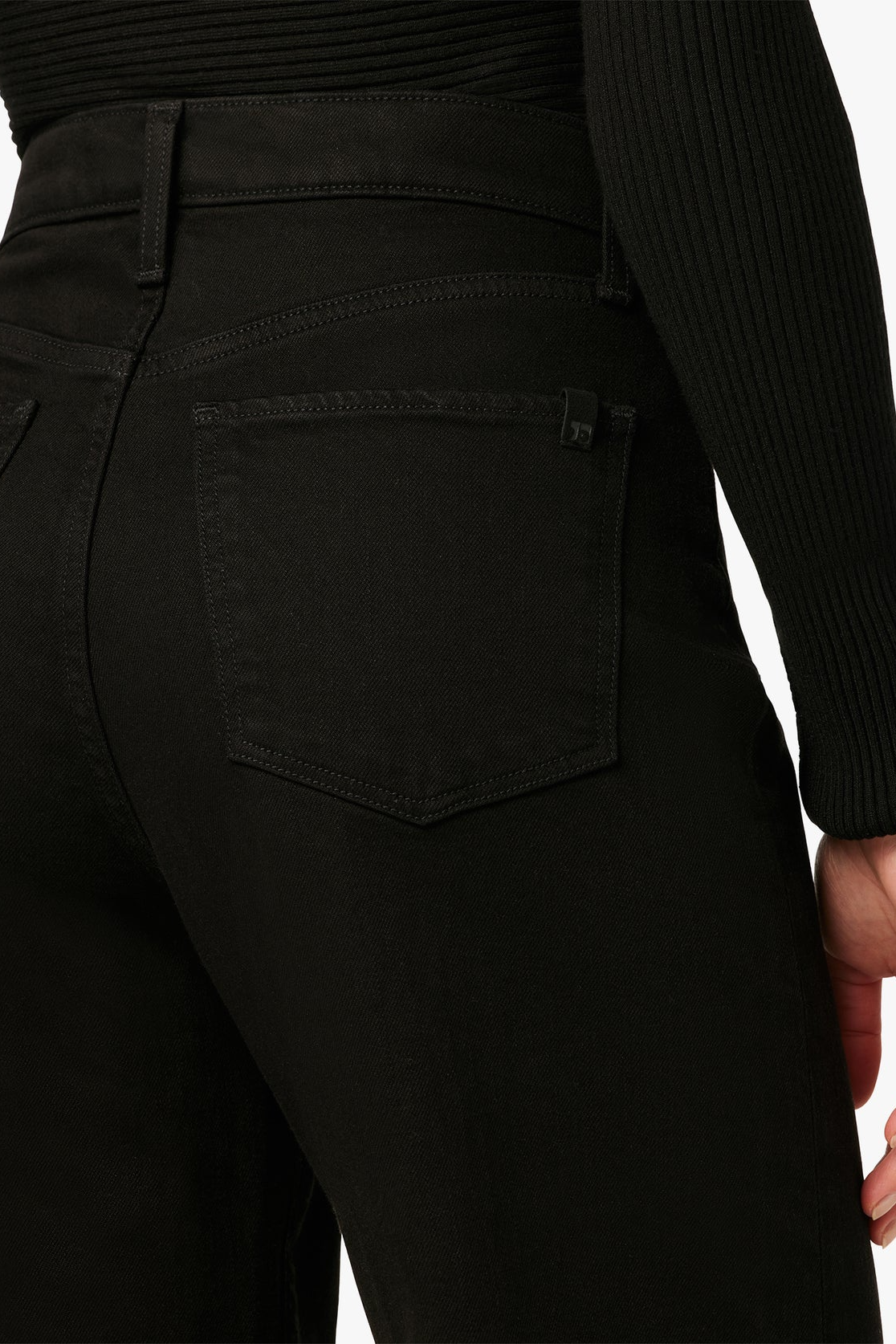 Close-up of black pants with a pocket detail on a white background