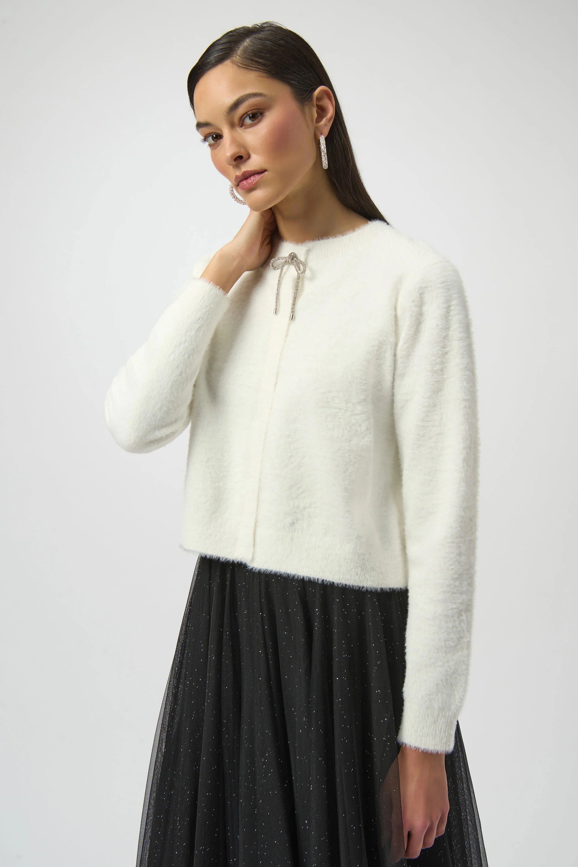 Woman wearing a white sweater with a black skirt on a plain background