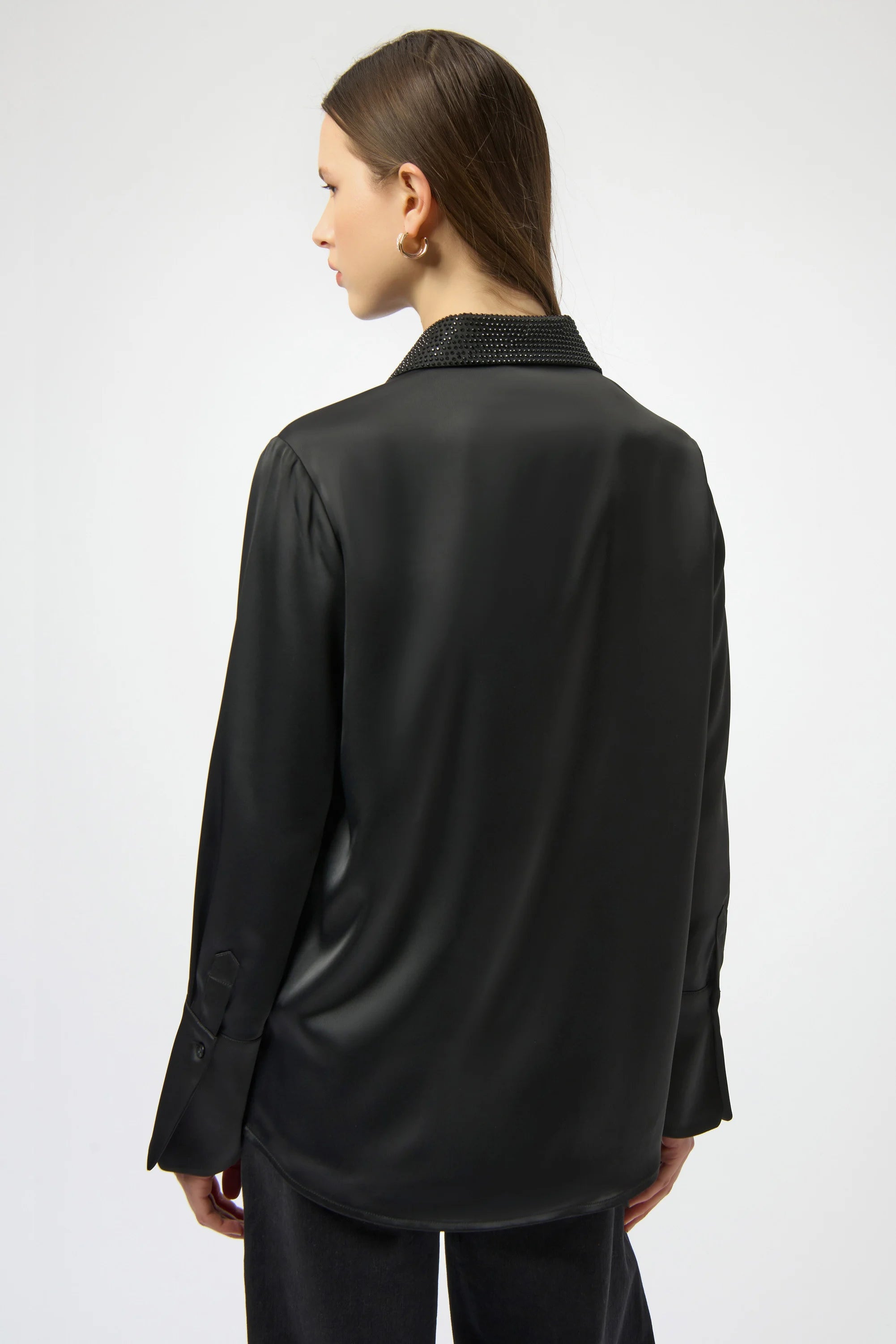 Person wearing a black satin shirt with a textured collar on a white background