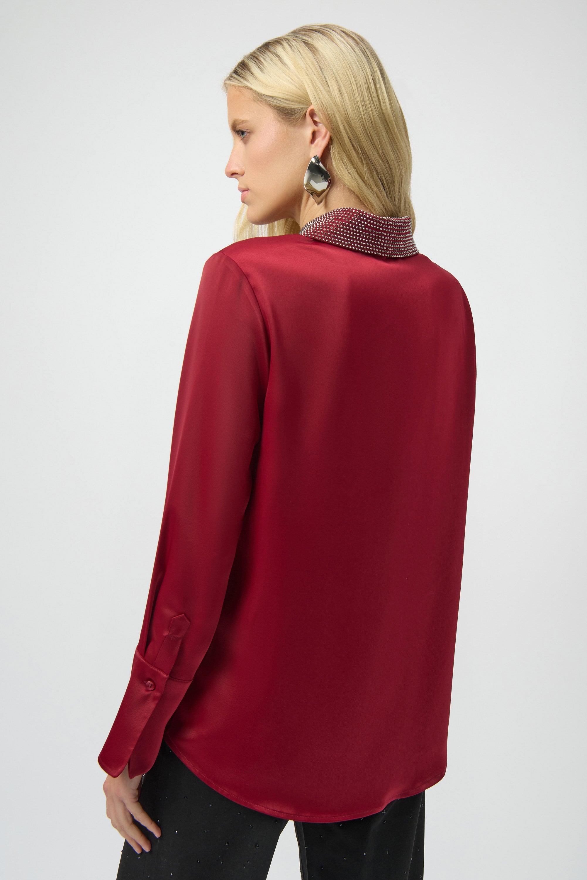 Woman wearing a red blouse with a textured collar on a white background