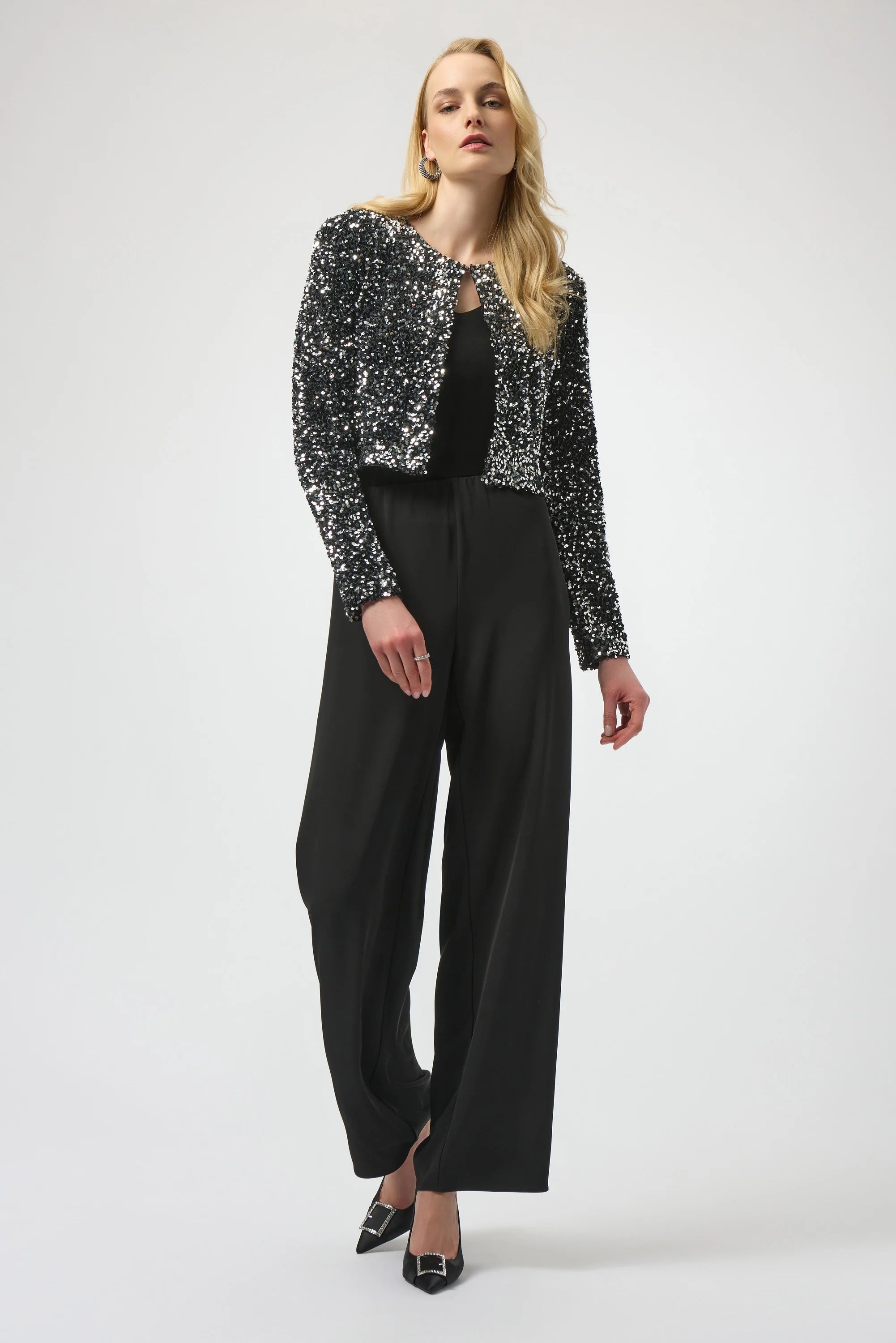 Woman wearing a sequin jacket and black pants on a white background