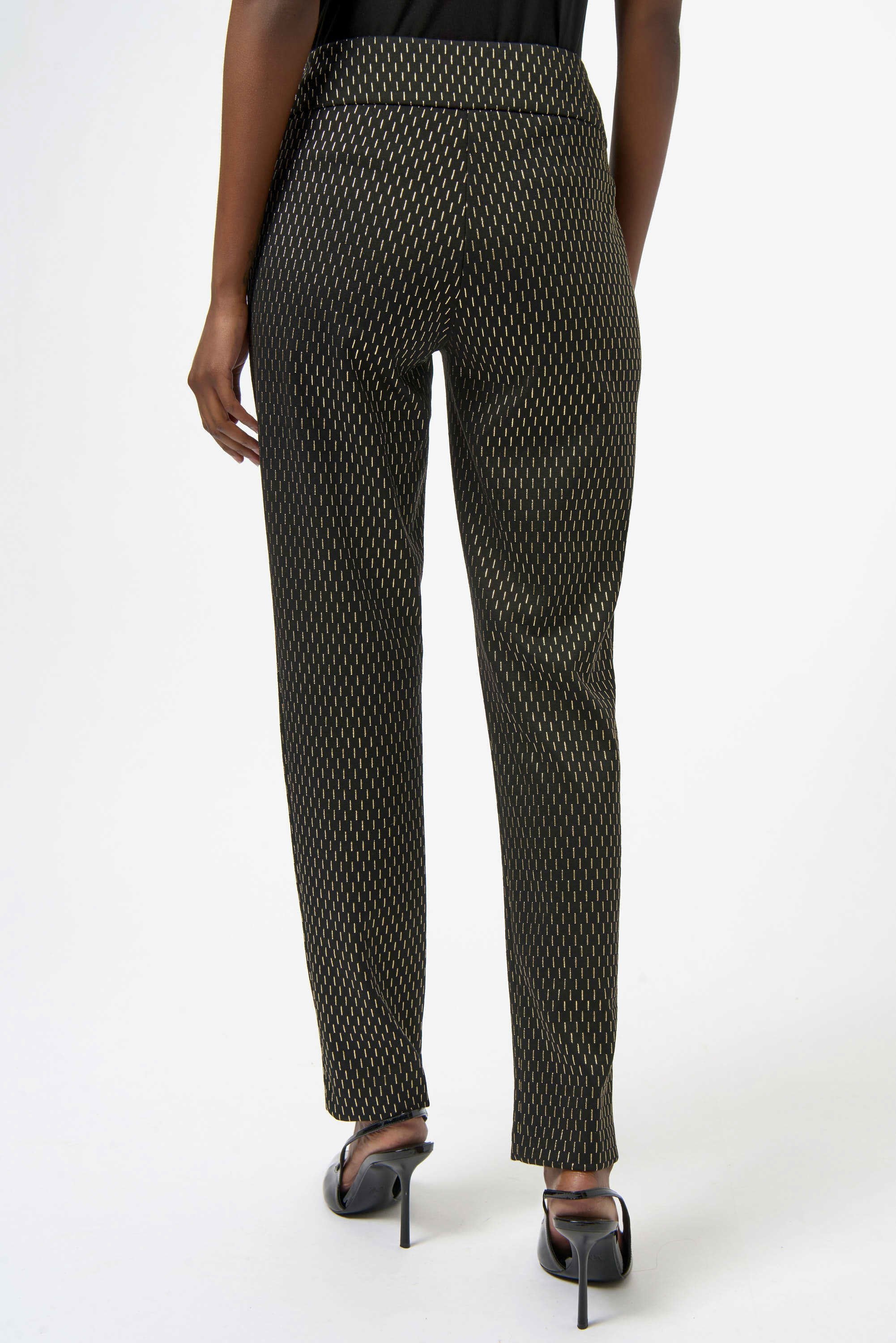 Black patterned pants worn by a person on a white background