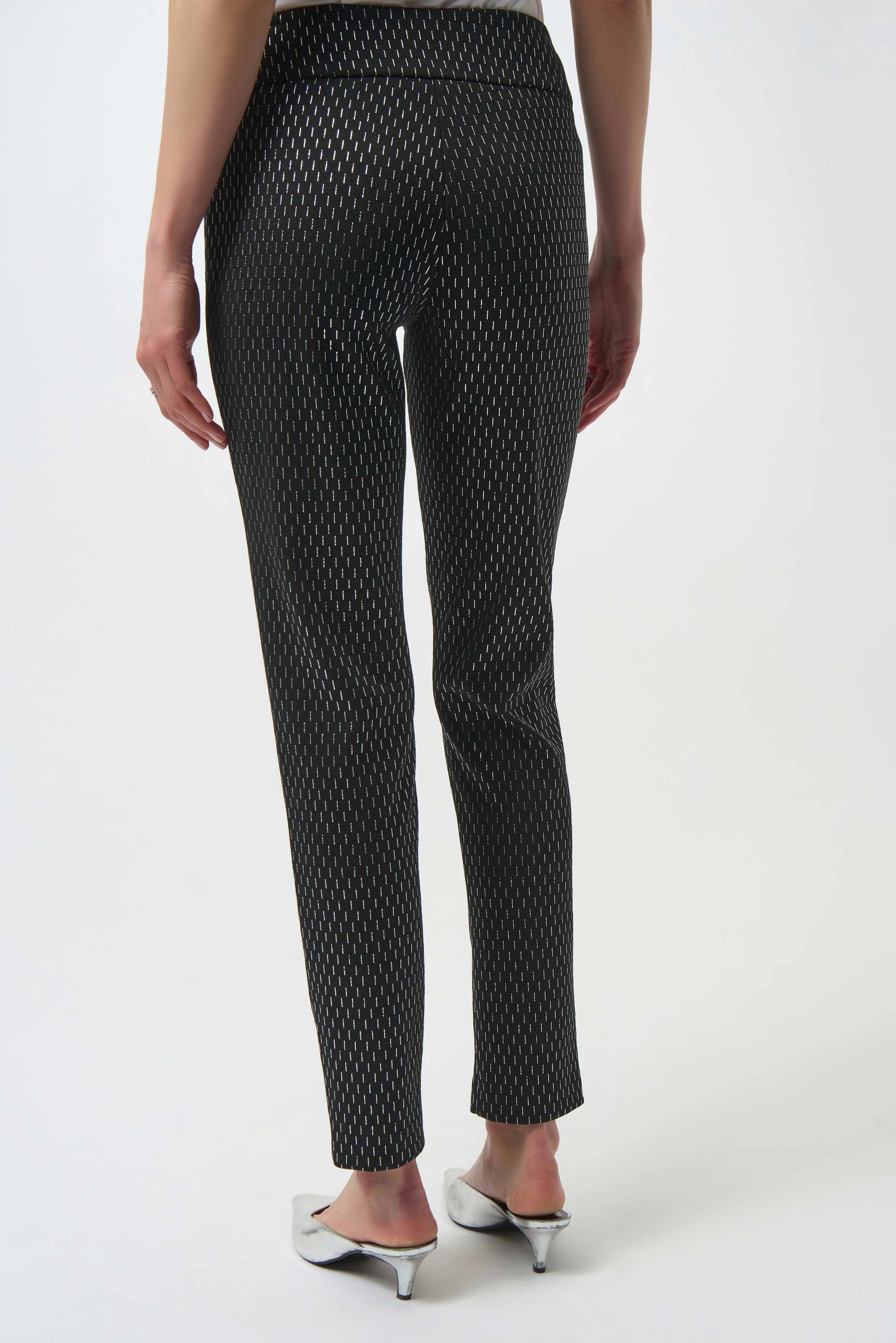 Black patterned pants worn by a person on a white background