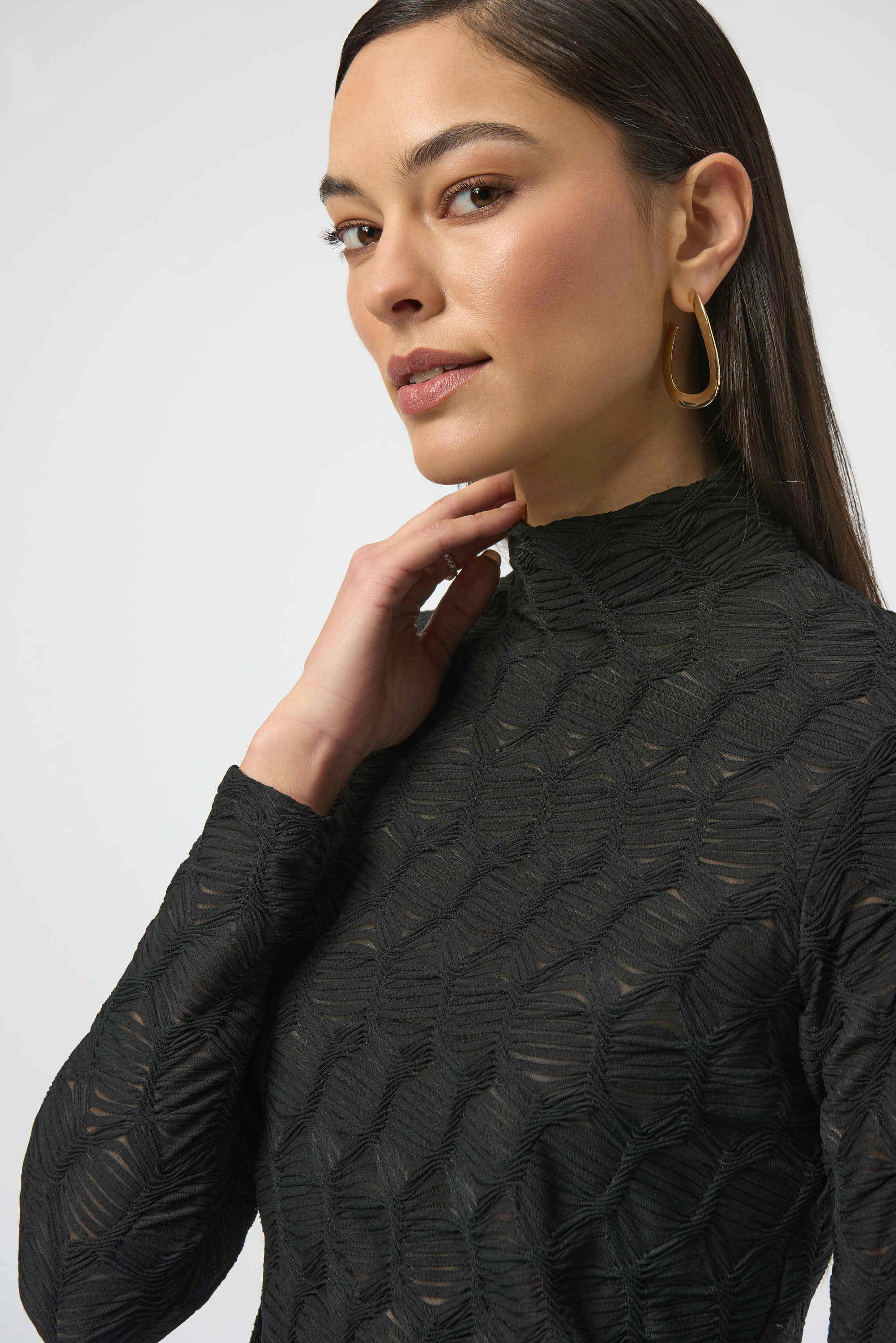 Woman wearing a black textured long-sleeve top against a white background