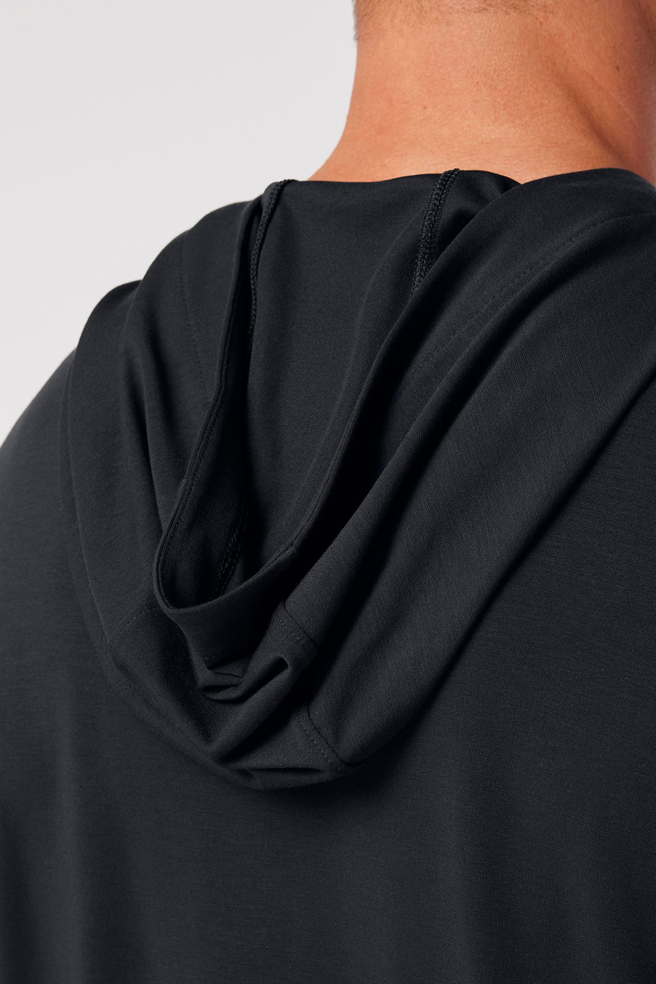 Close-up of a black garment with a hood on a plain background