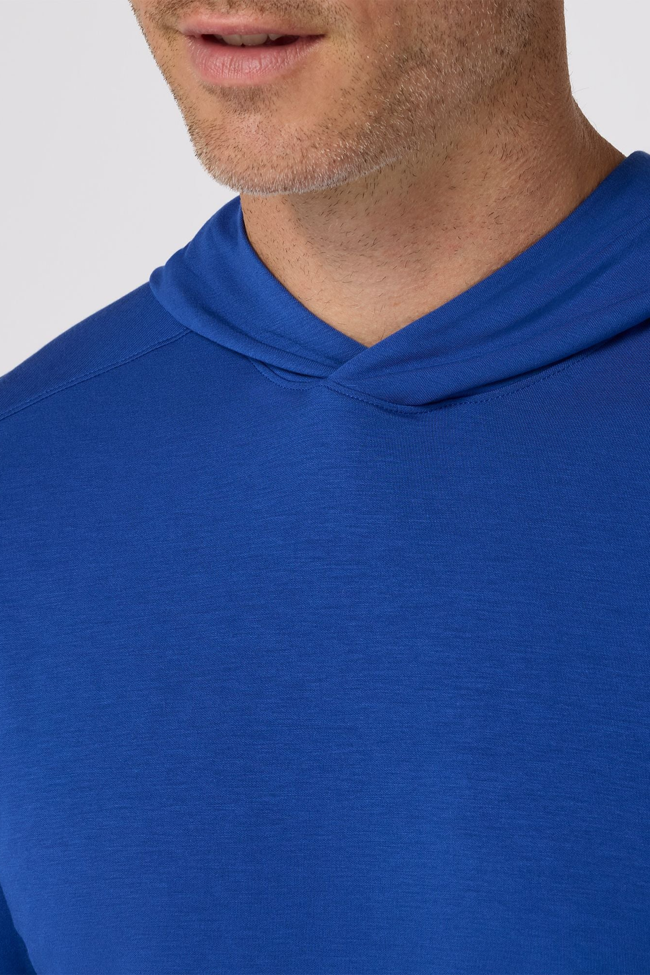 Close-up of a person wearing a blue hoodie with a plain background