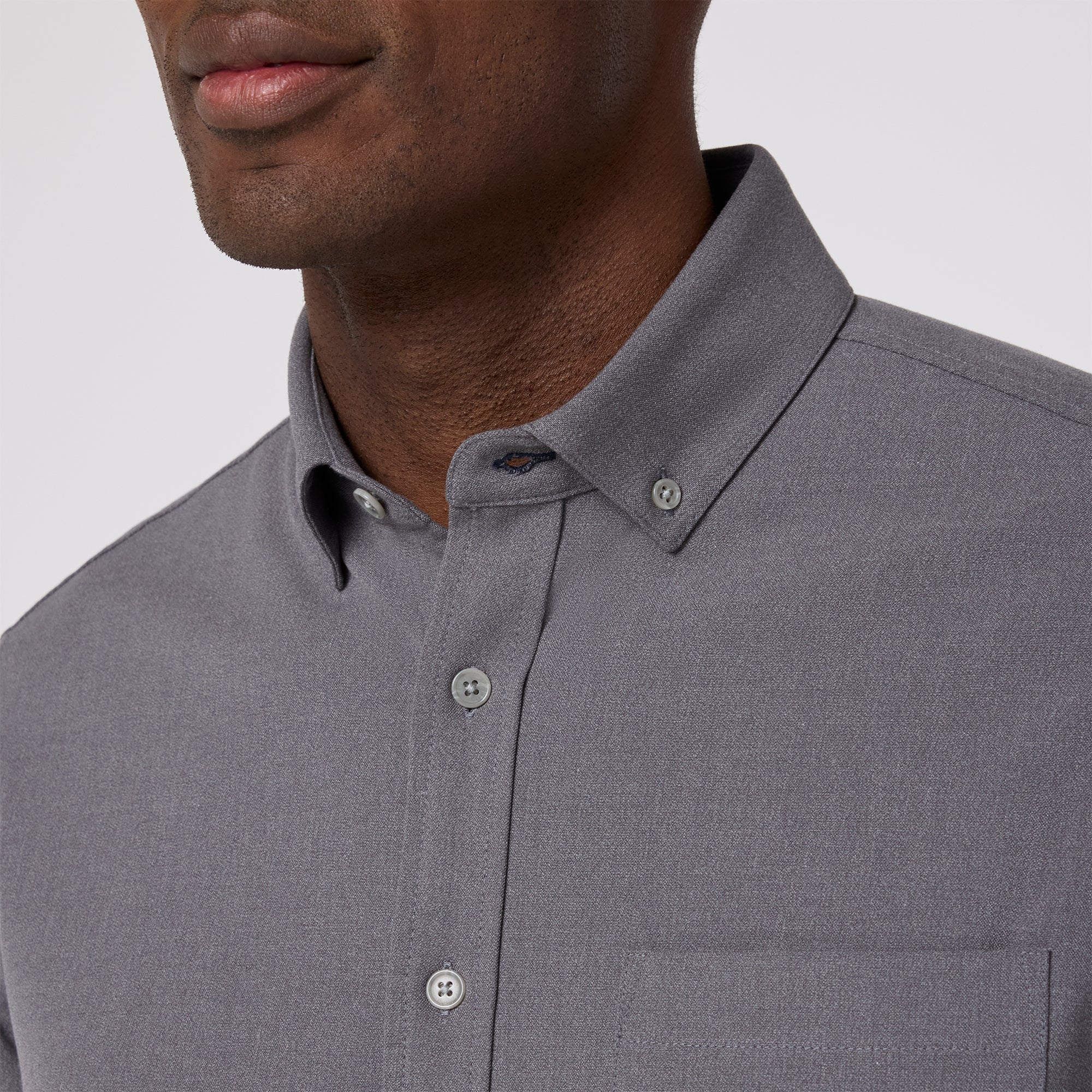 Gray button-up shirt worn by a person on a plain background