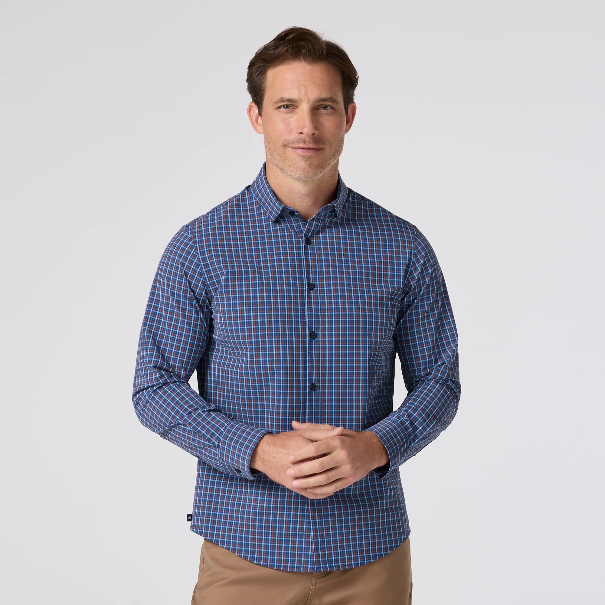 Man wearing a blue checkered shirt on a light gray background