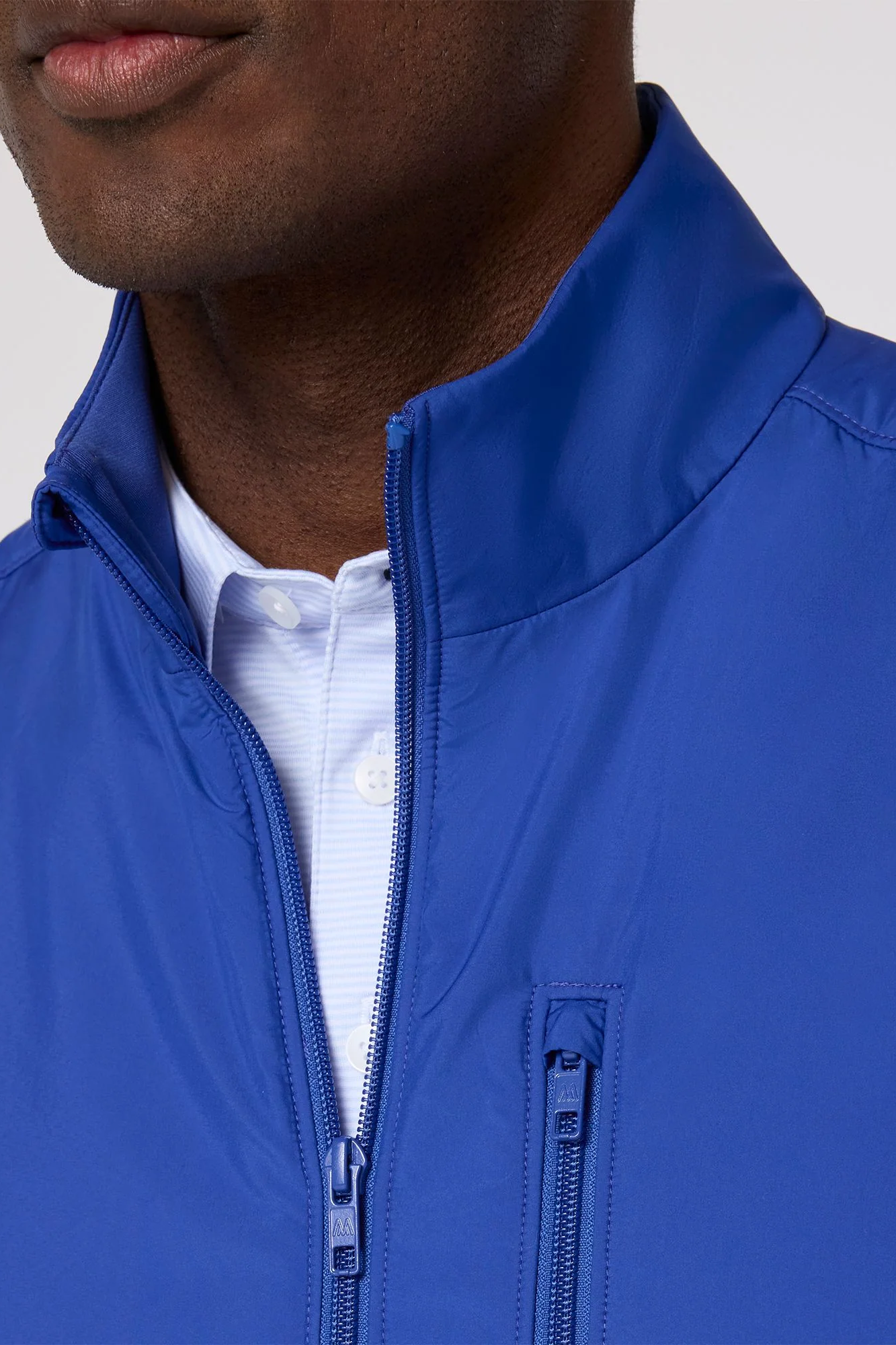 Close-up of a person wearing a blue jacket with a white shirt underneath.
