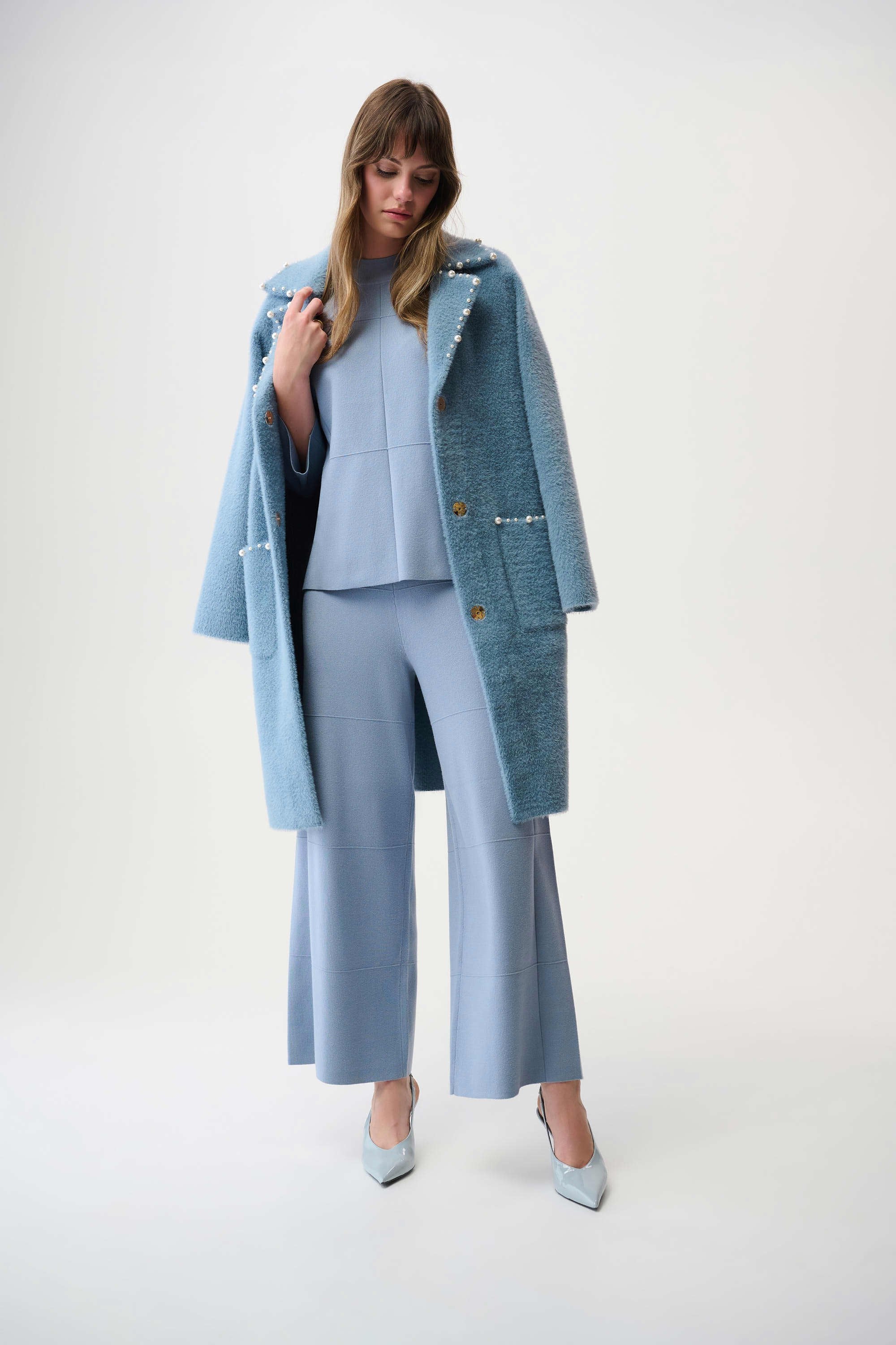 Woman wearing a light blue coat over a matching outfit on a white background