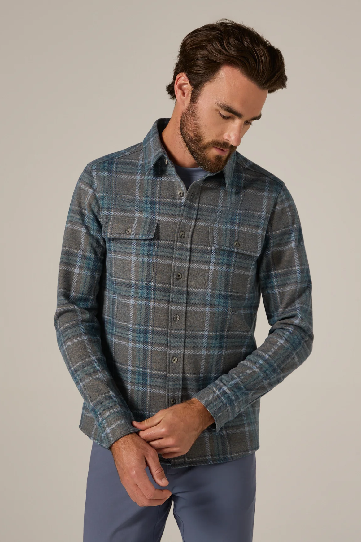 Man wearing a plaid shirt and blue pants against a neutral background