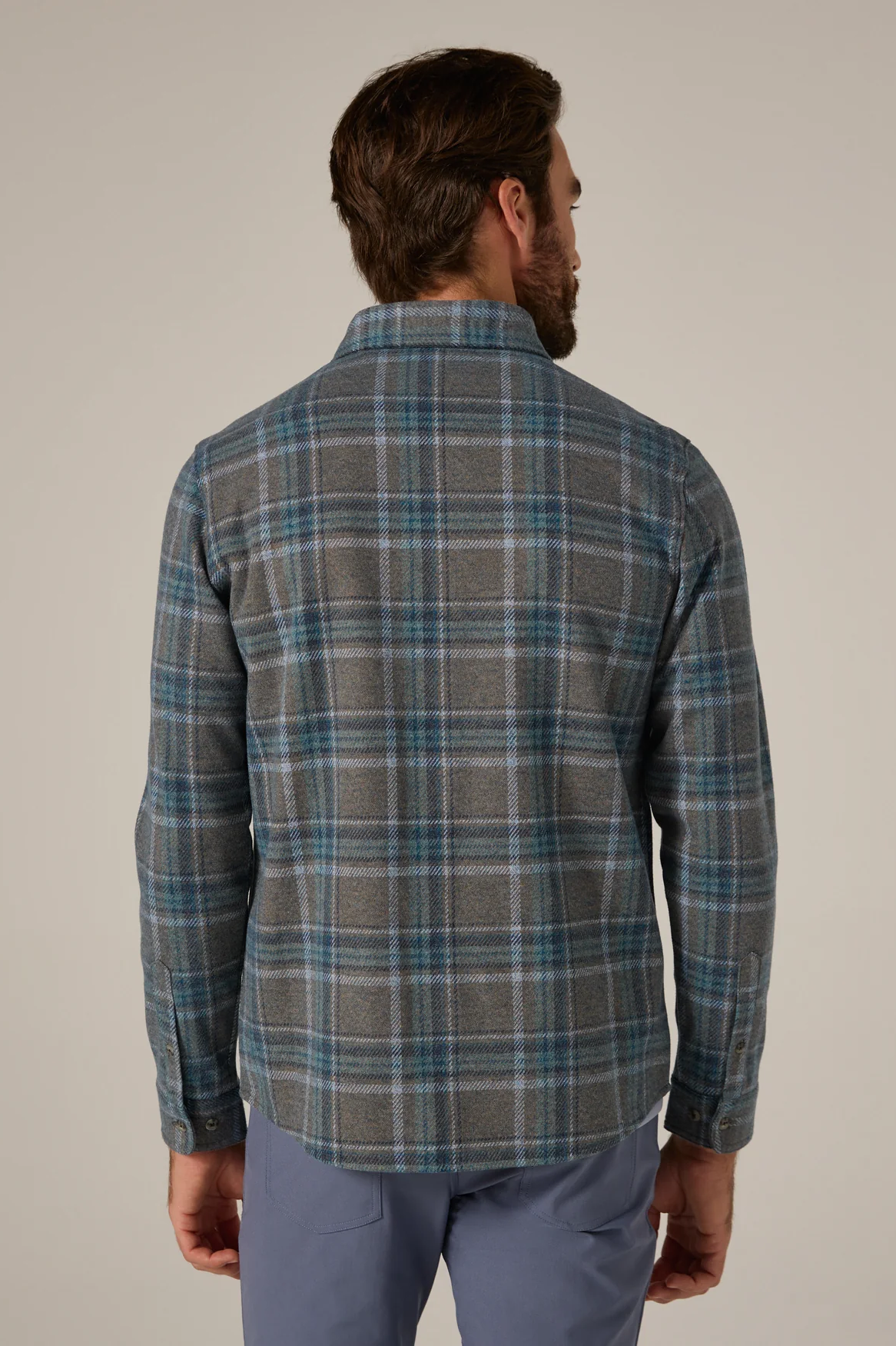 Man wearing a plaid shirt and pants against a plain background
