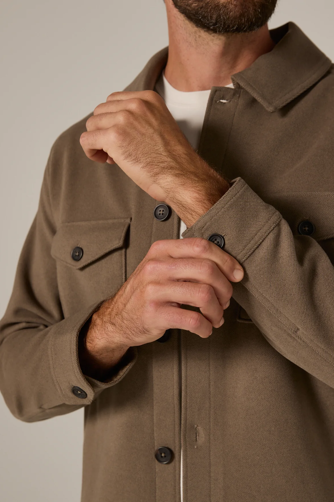 Man wearing a brown jacket with a neutral background
