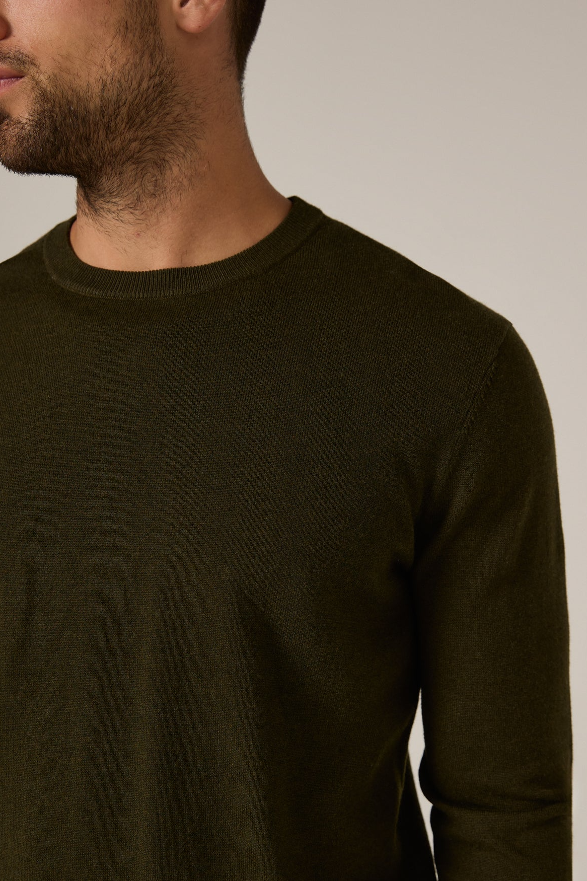Man wearing a dark brown sweater against a neutral background