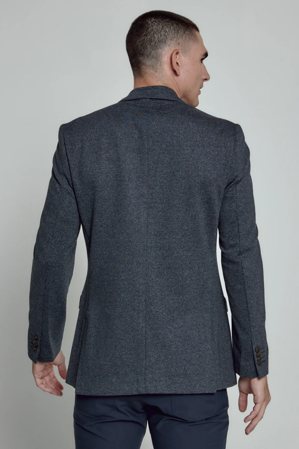 Man wearing a dark gray suit jacket on a plain background