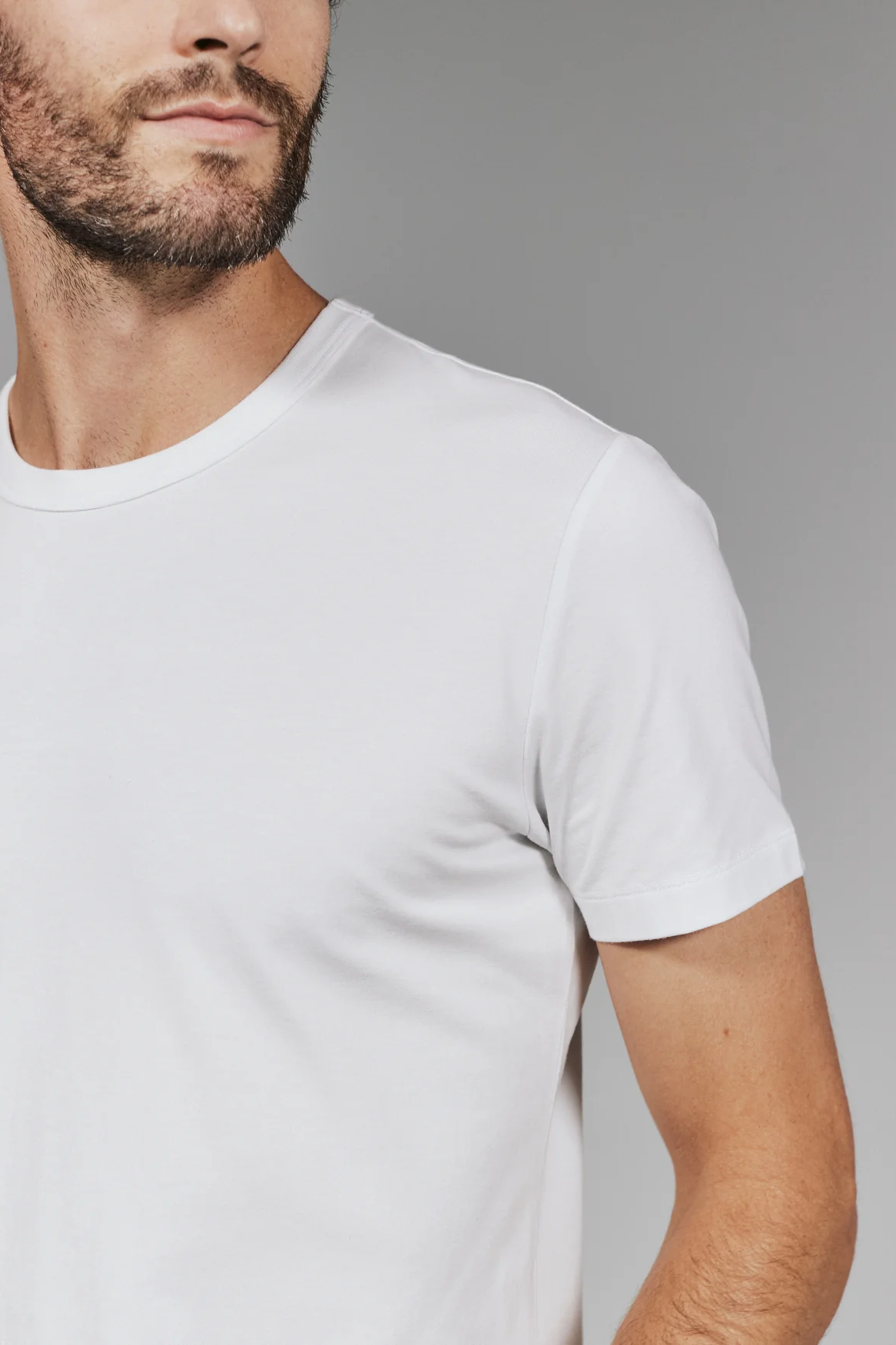 Man wearing a plain white t-shirt against a gray background