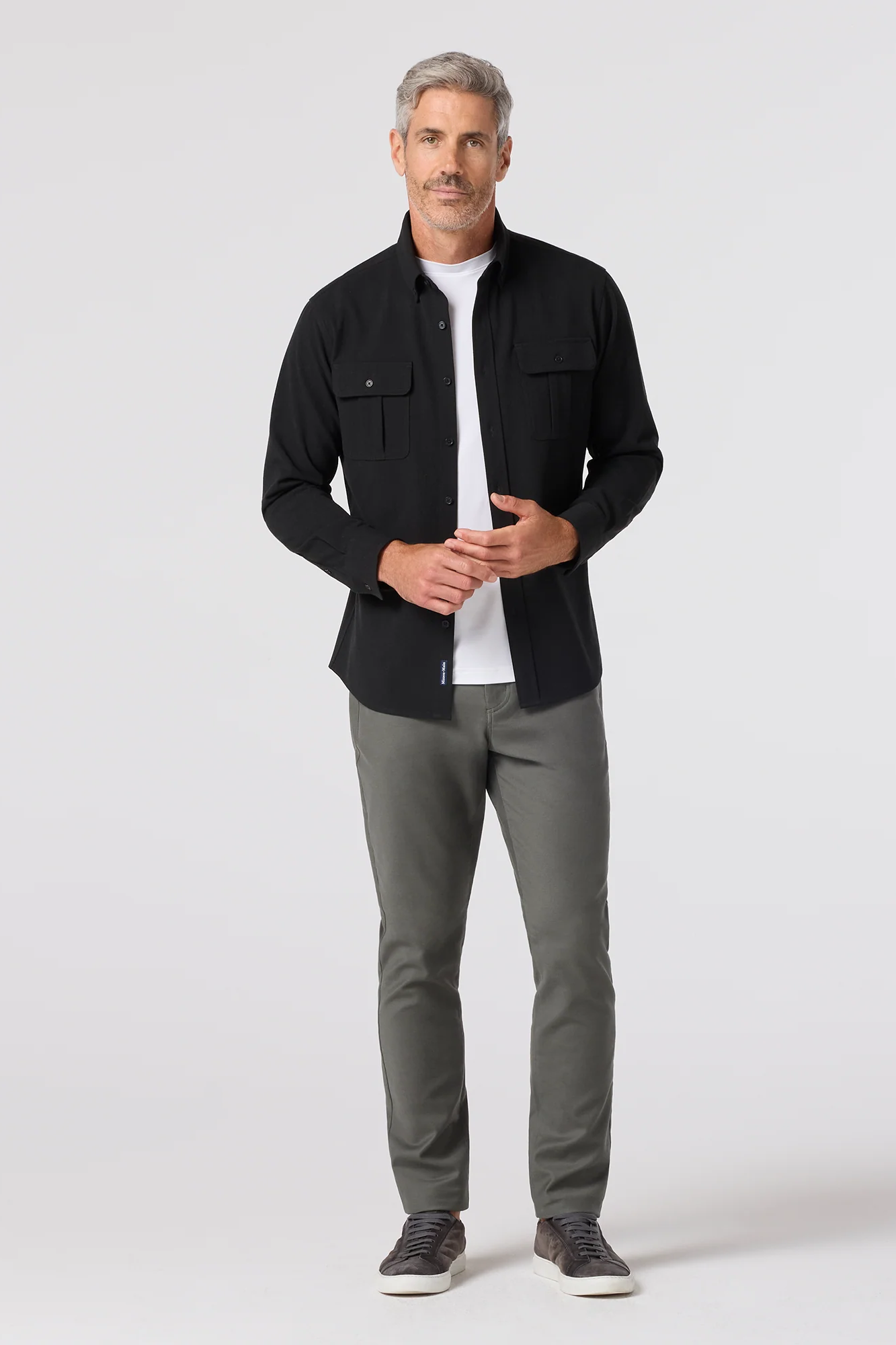Man wearing a black jacket, white shirt, and gray pants on a white background