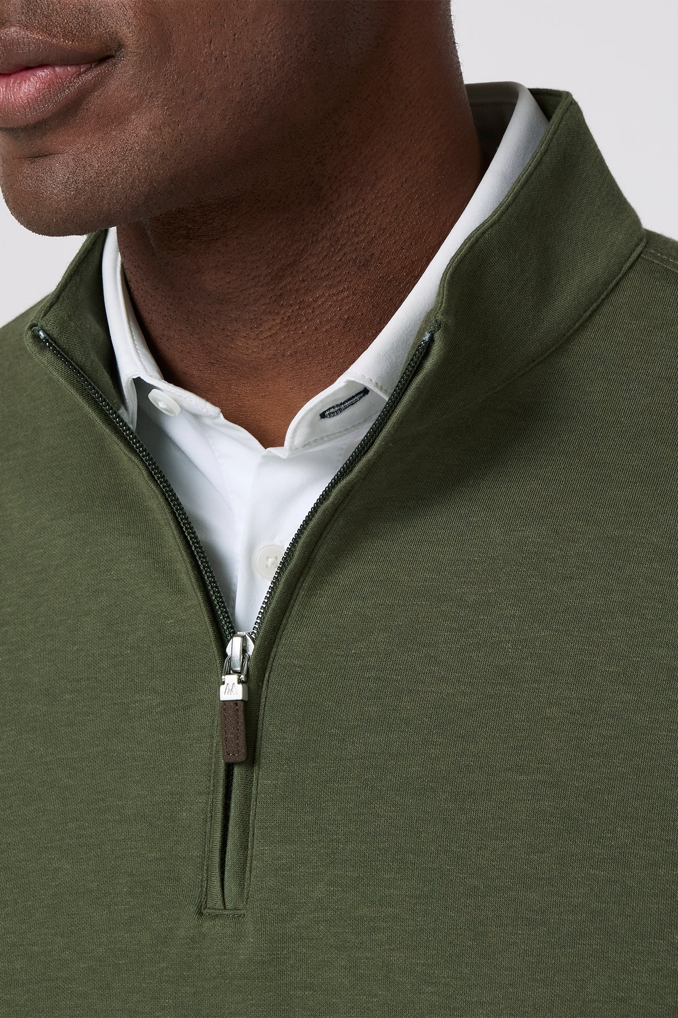 Close-up of a person wearing a green zip-up sweater over a white shirt.