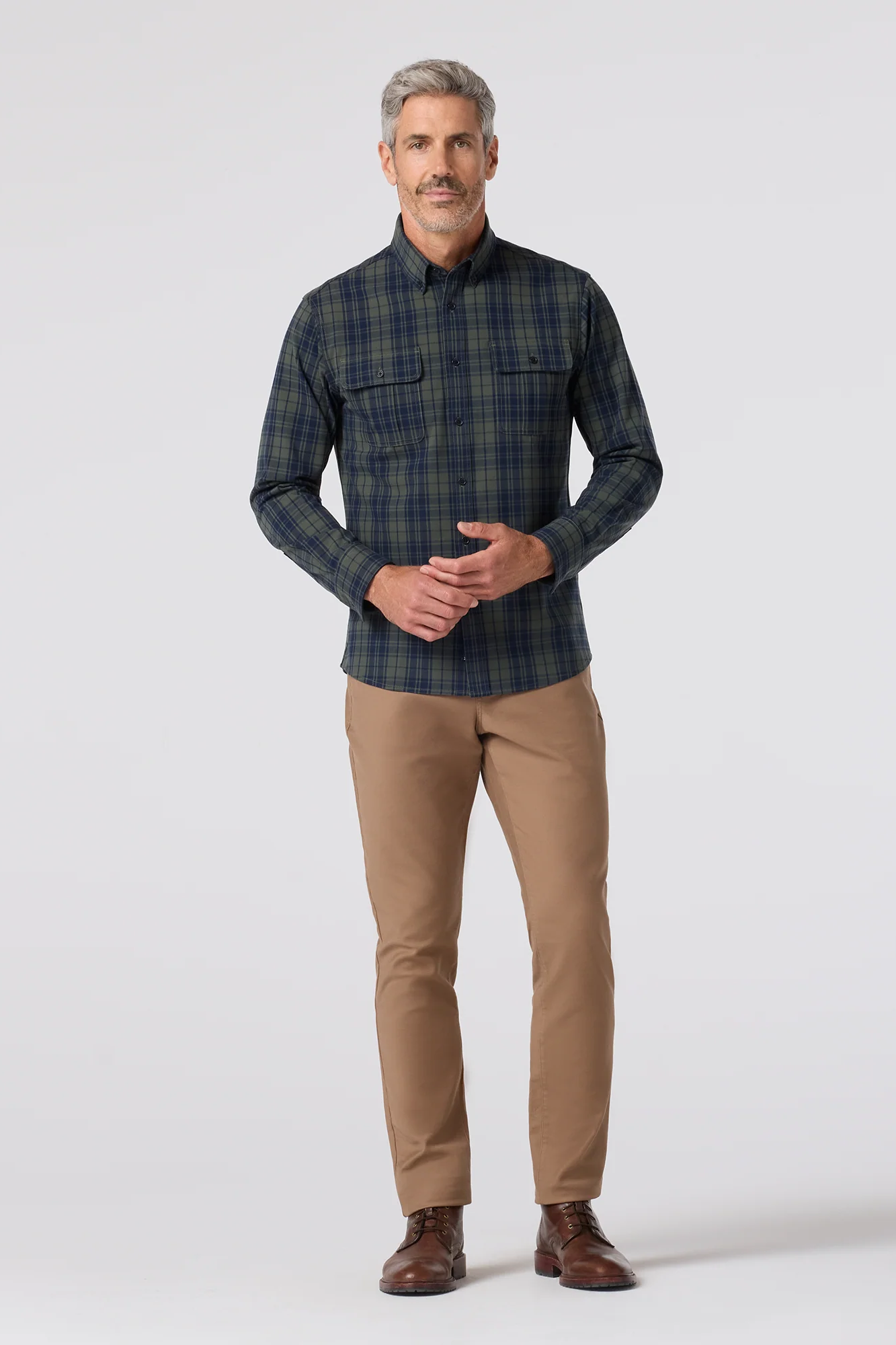 Man wearing a plaid shirt and beige pants on a white background