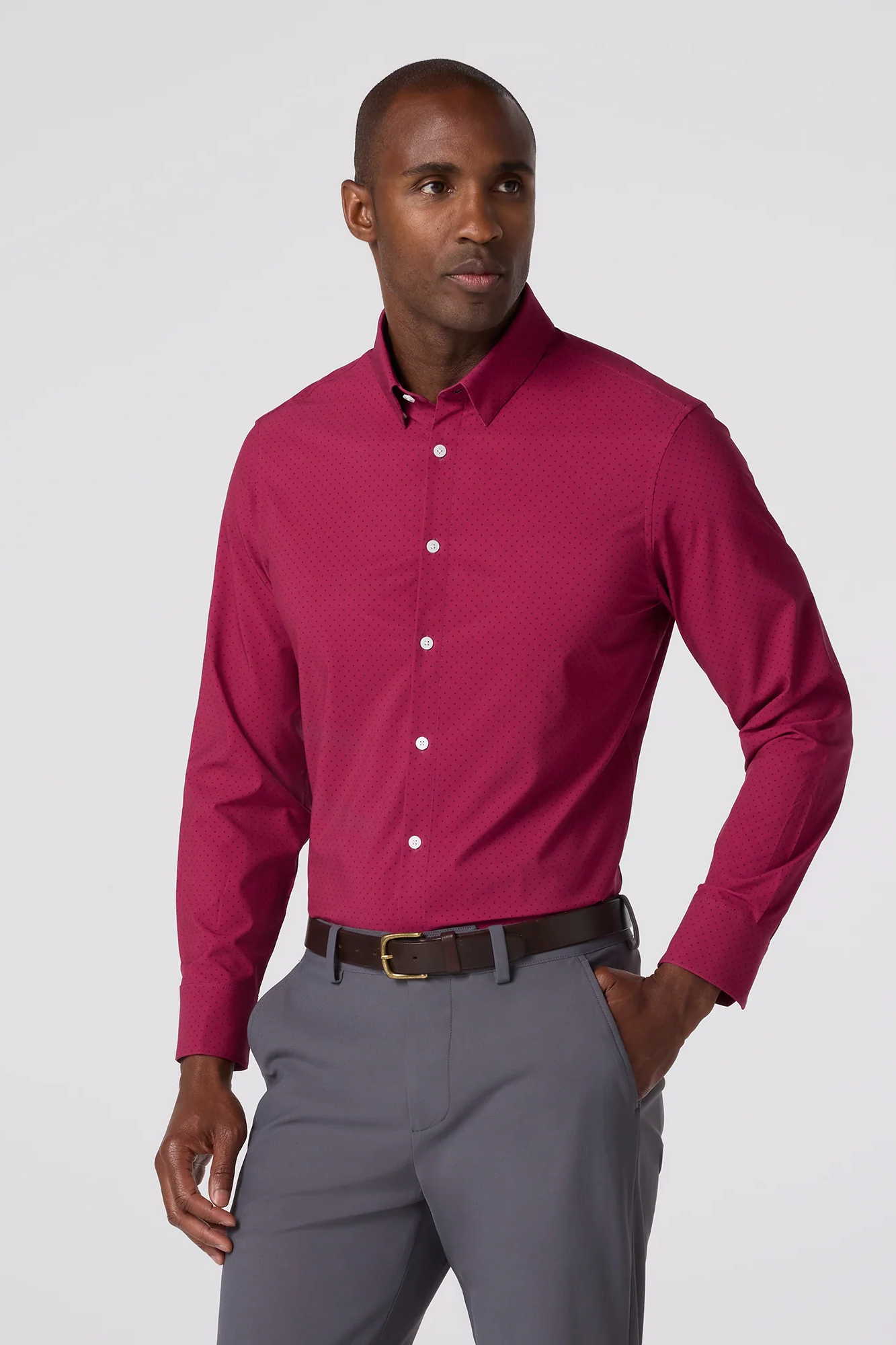 Man wearing a magenta shirt and gray pants on a white background