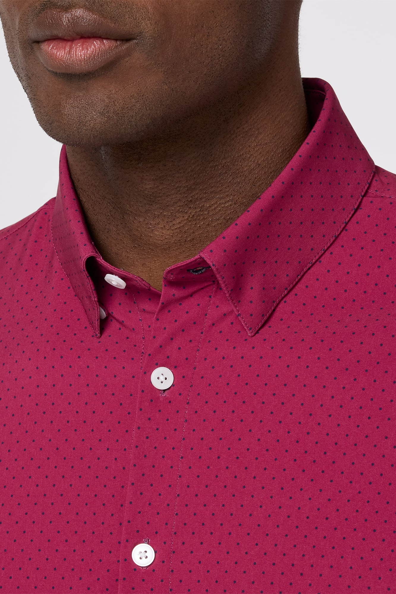 Close-up of a person wearing a pink shirt with a subtle pattern.