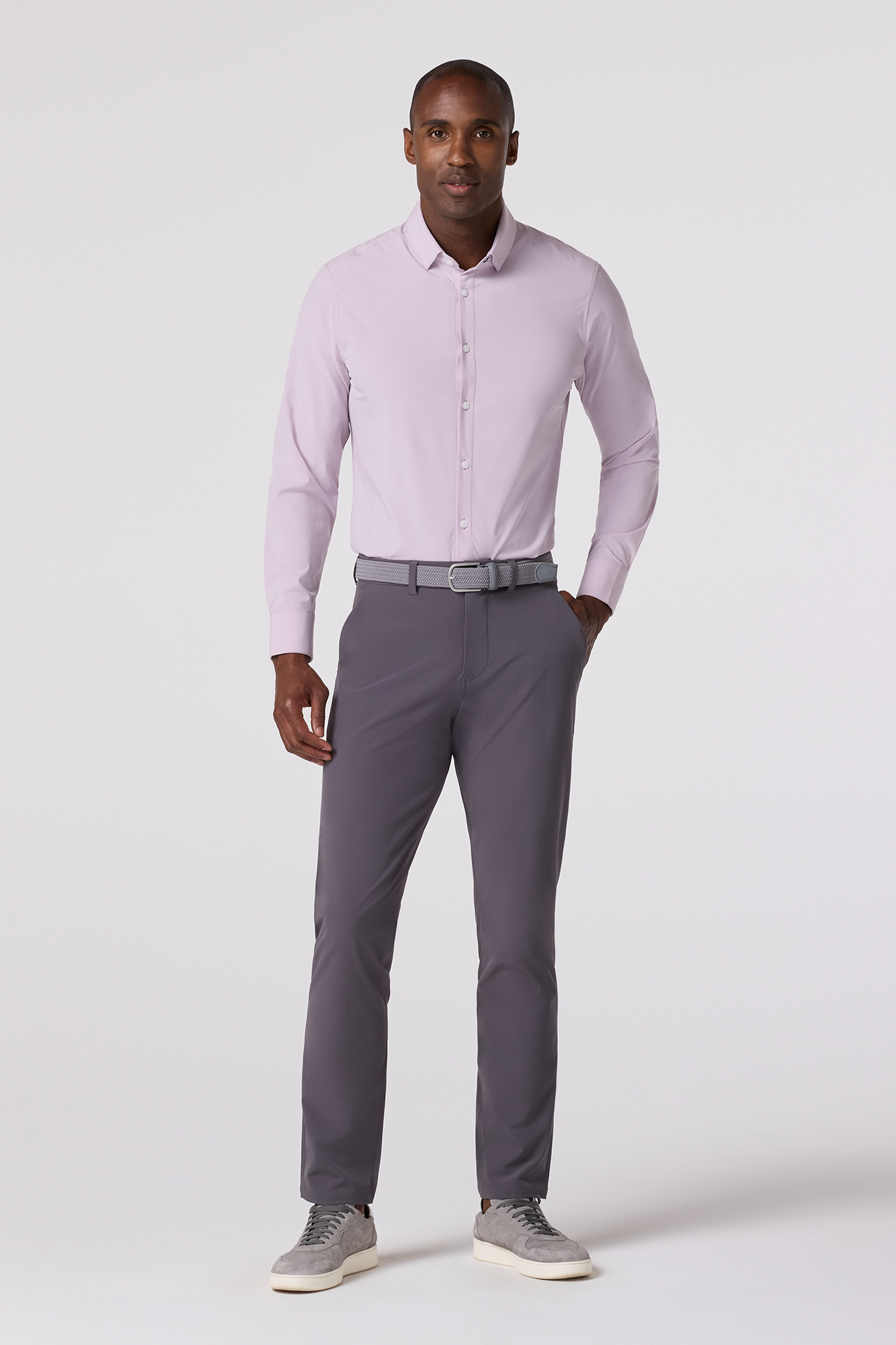 Man wearing a light purple dress shirt and gray pants on a white background