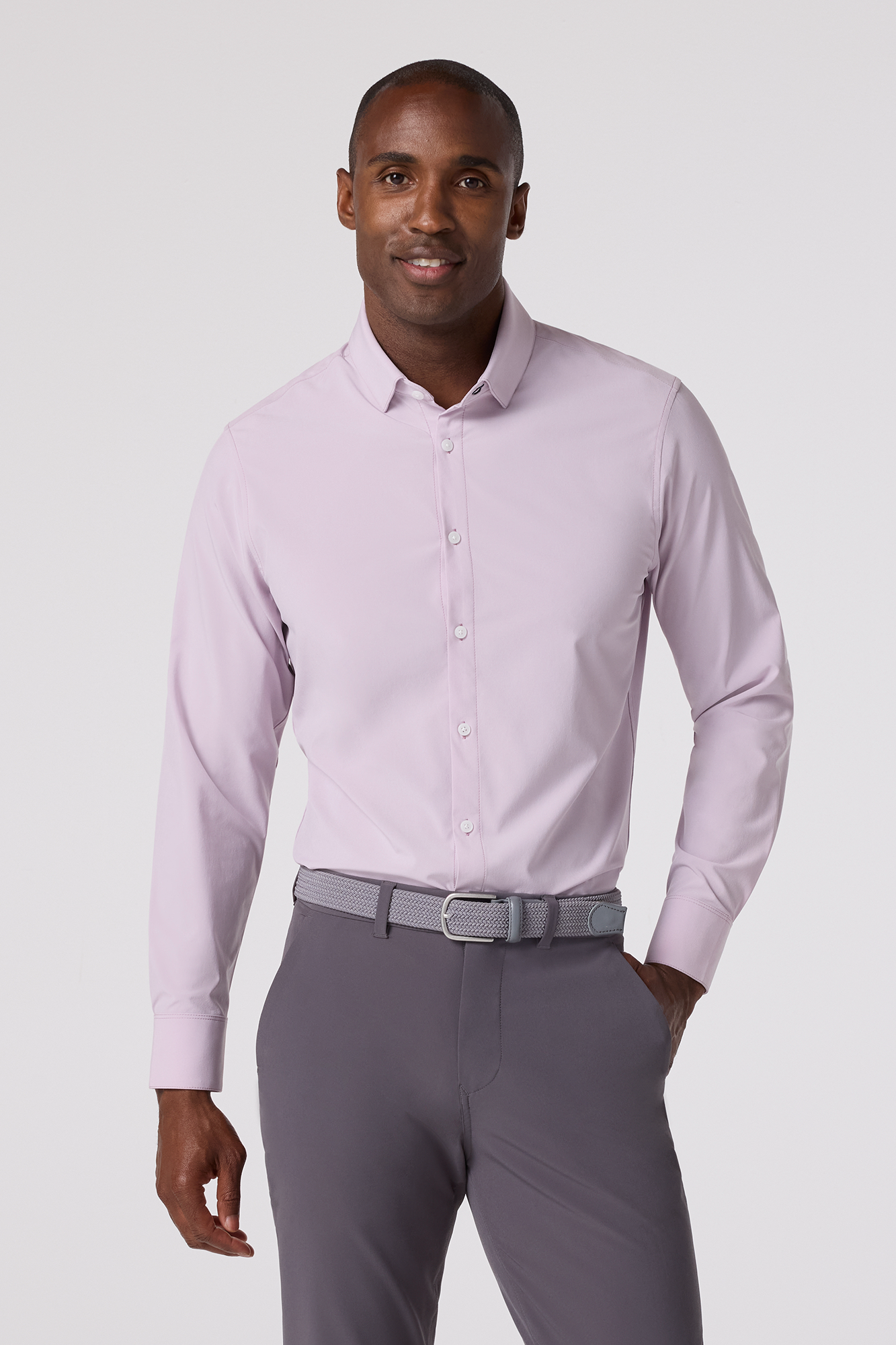 Man wearing a light purple dress shirt and gray pants on a white background